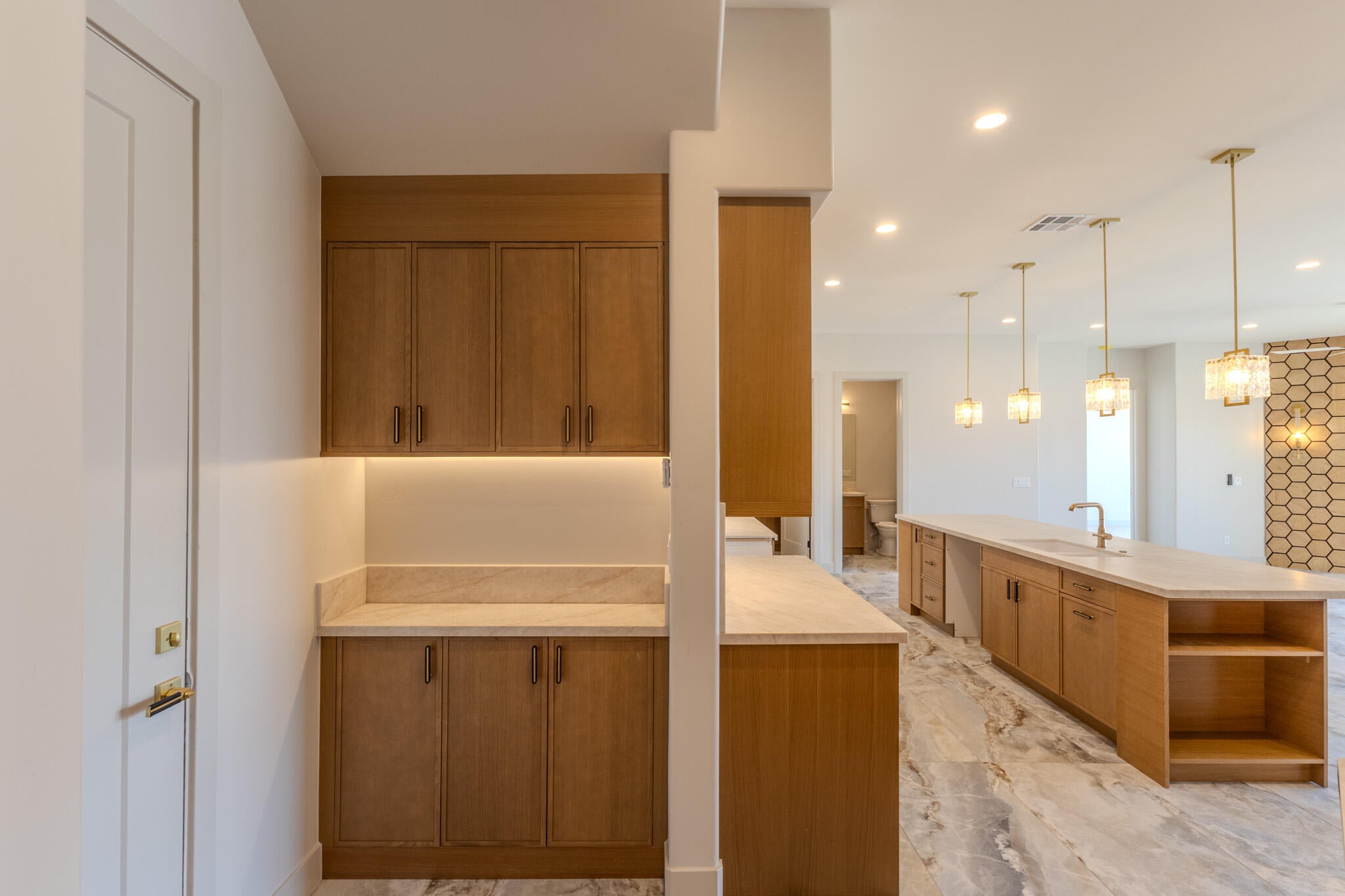 Kitchen area featuring a built-in wet bar with wooden cabinetry, under-cabinet lighting, and light-toned countertops