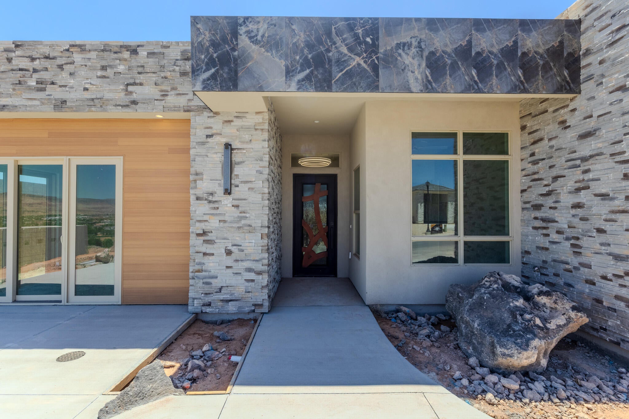 Modern architectural facade featuring stone veneer accents, wood-finish siding, and a prominent entry