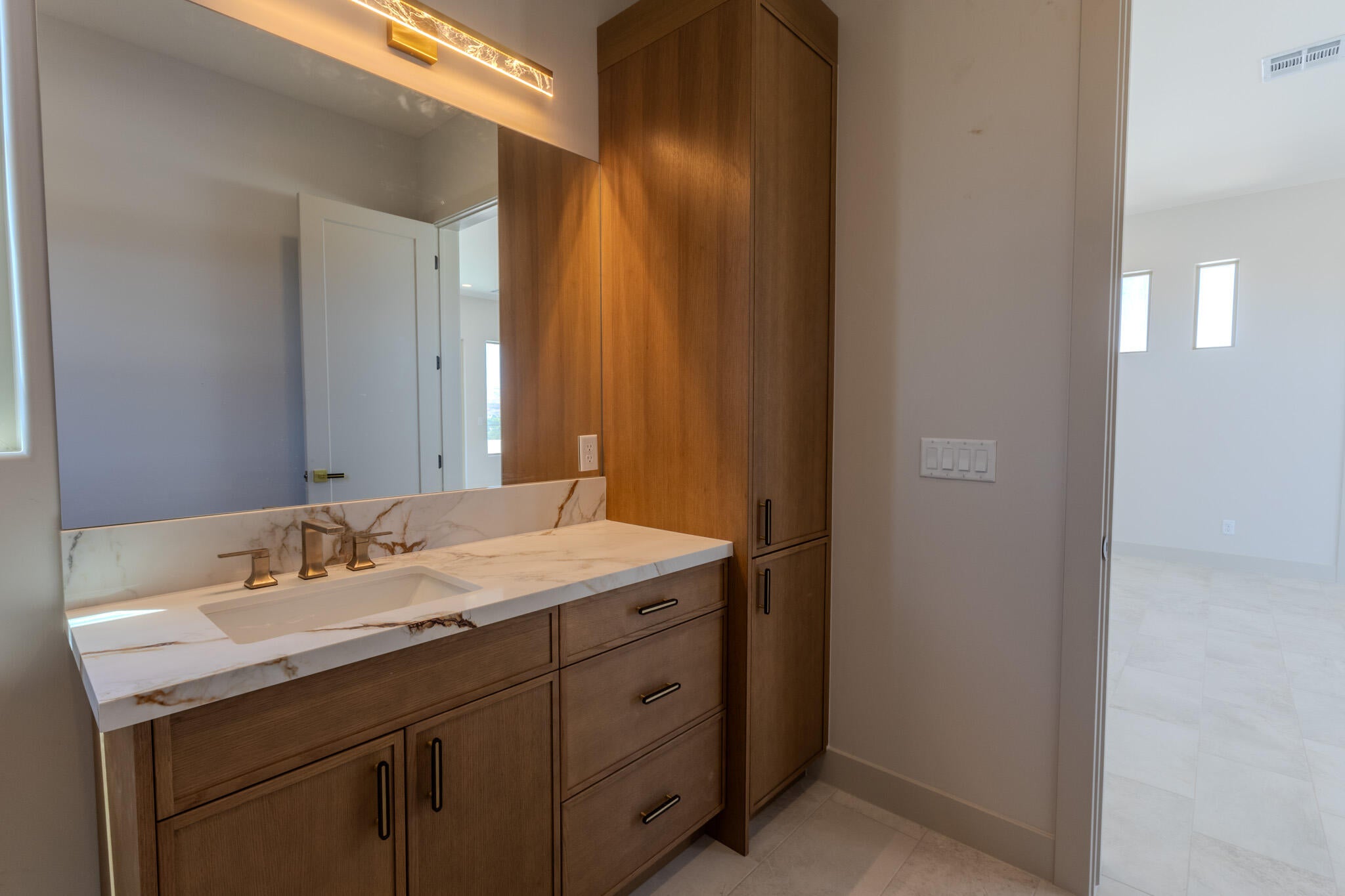 Bathroom vanity featuring a rectangular undermount sink, a stone countertop with prominent veining, and a three-piece gold-tone faucet