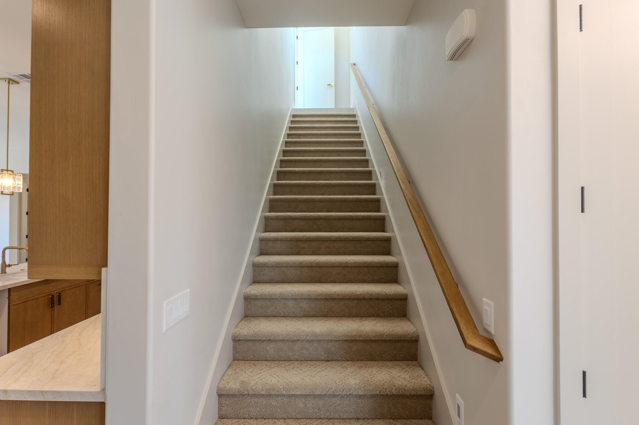 Carpeted staircase with a wood-finish handrail