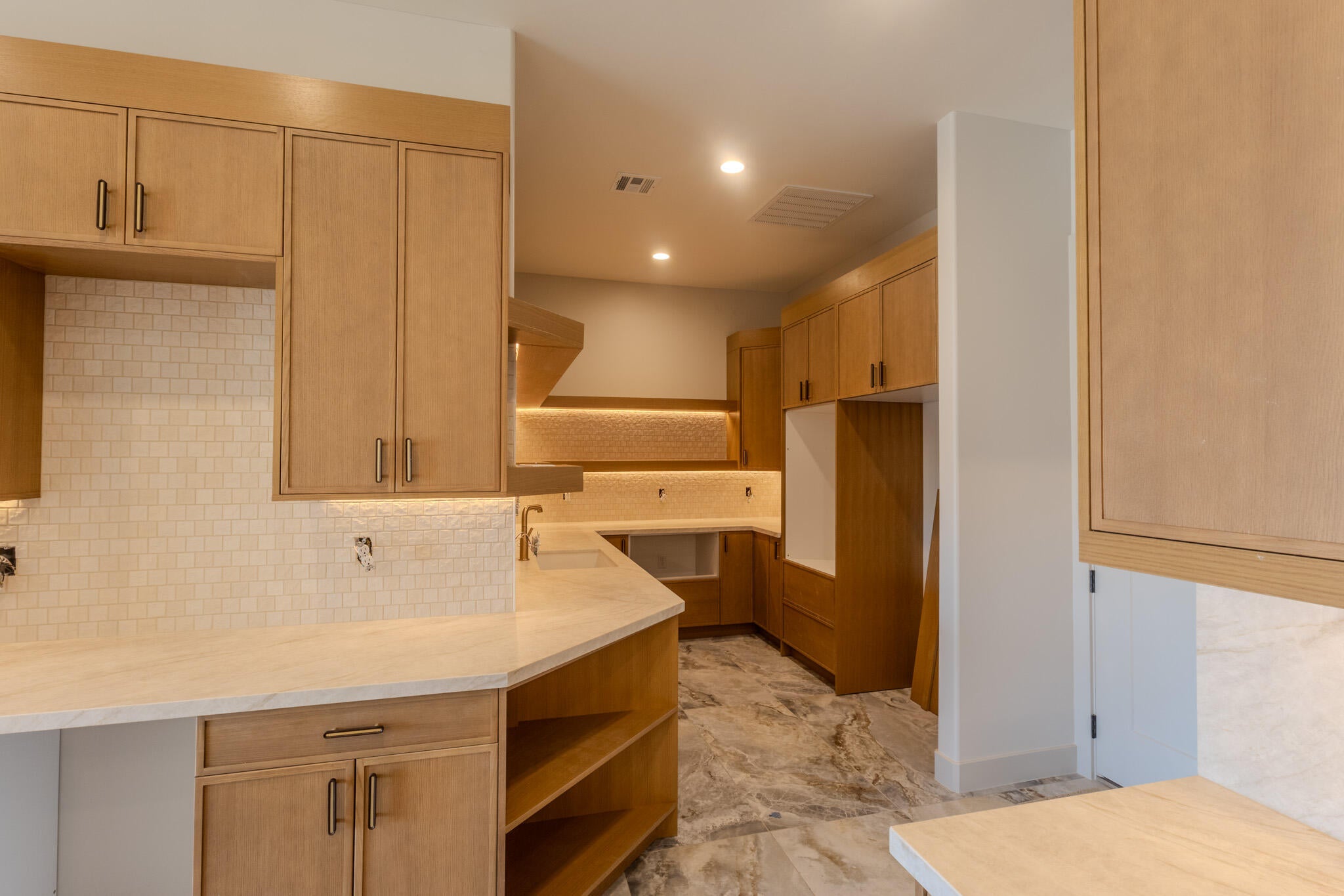 Kitchen featuring light wood-finish cabinetry, light stone countertops, and a subway tile backsplash