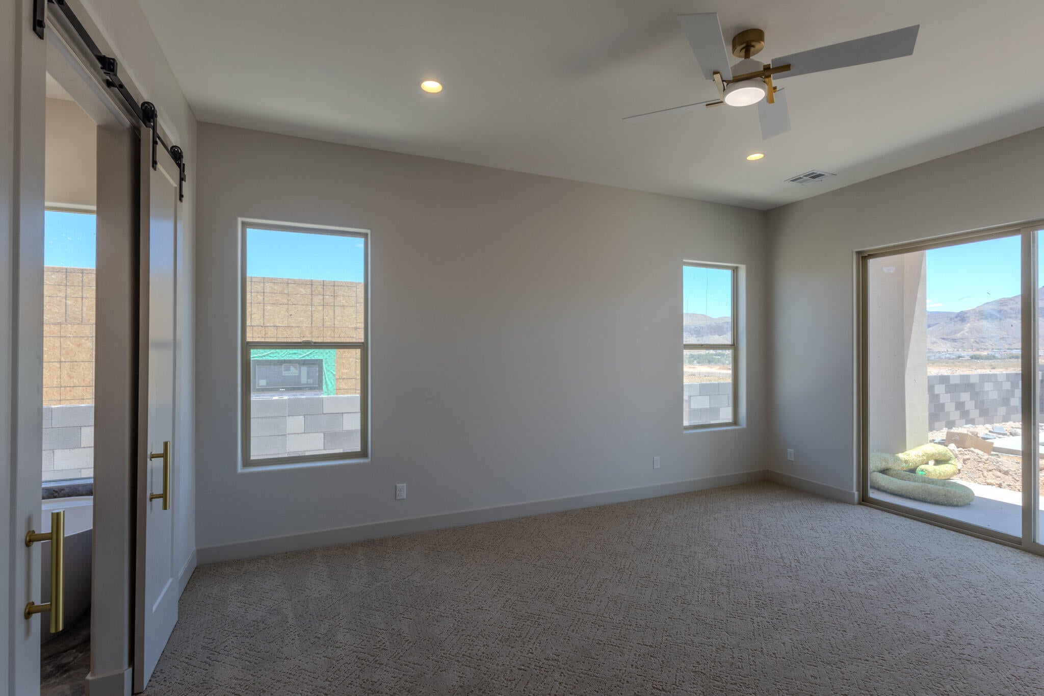 Spacious room featuring neutral carpeting, a ceiling fan with integrated lighting, recessed lighting, and a sliding glass door providing outdoor access