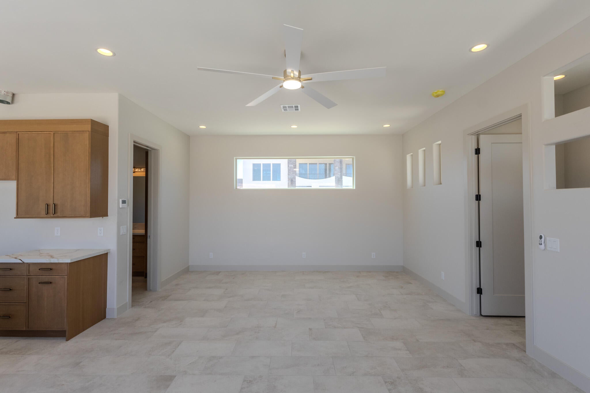 Spacious room featuring light-toned tile flooring, recessed lighting, and a ceiling fan