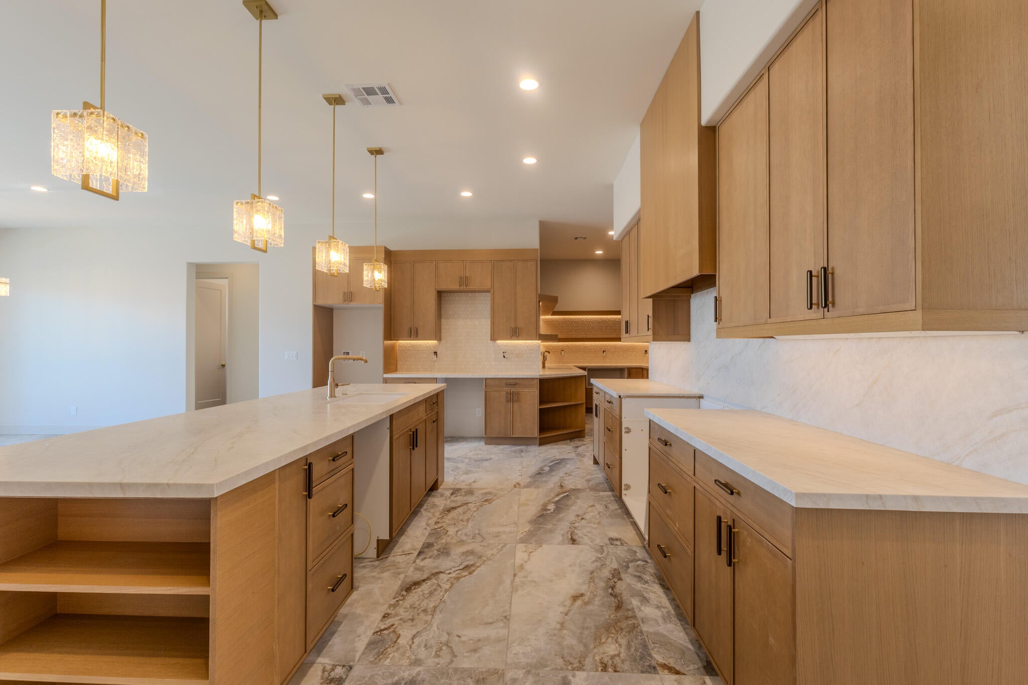 Spacious kitchen featuring light wood-finish cabinetry, light-toned countertops, and a full-height backsplash