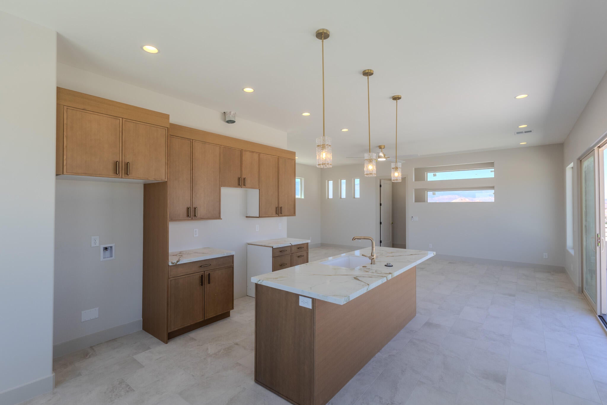 Modern kitchen featuring light wood-finish cabinetry, white countertops, and a central island with a gold-tone faucet