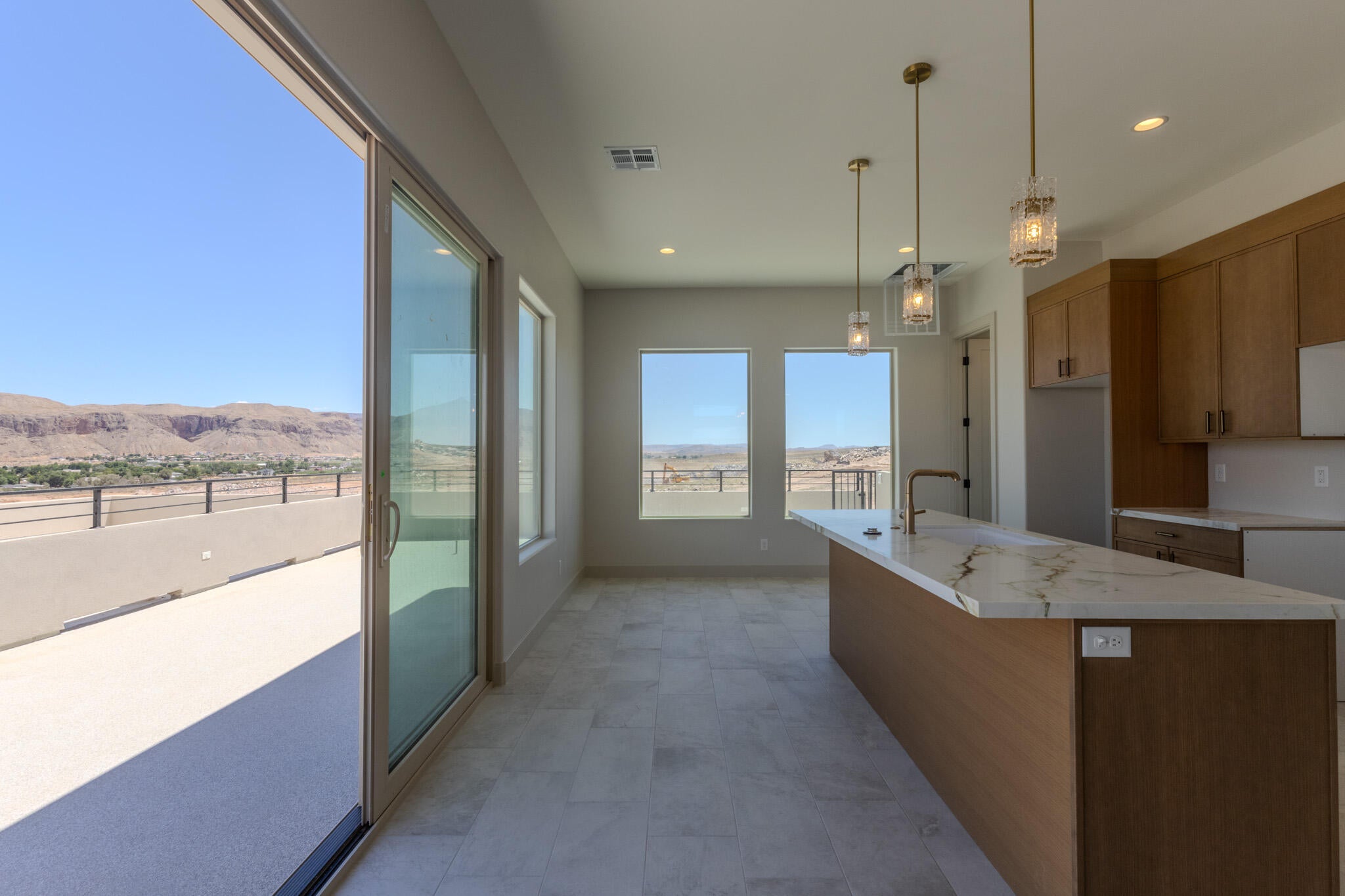 Spacious living area featuring a large sliding glass door opening to an outdoor patio with a mountain backdrop