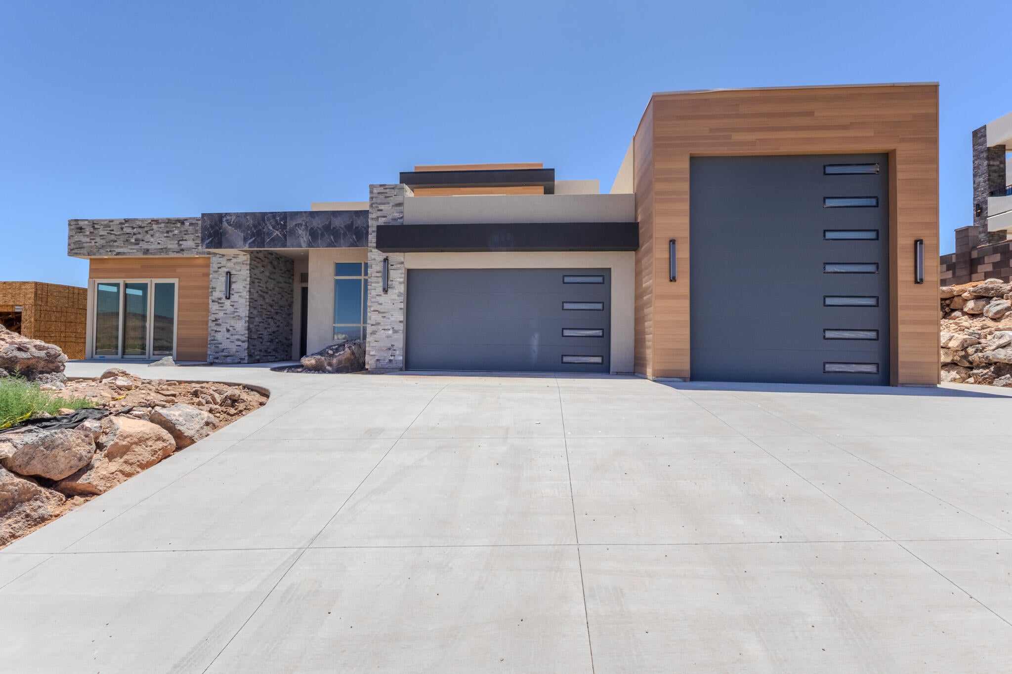 Modern facade featuring stone accents, wood-finish siding, and a concrete driveway