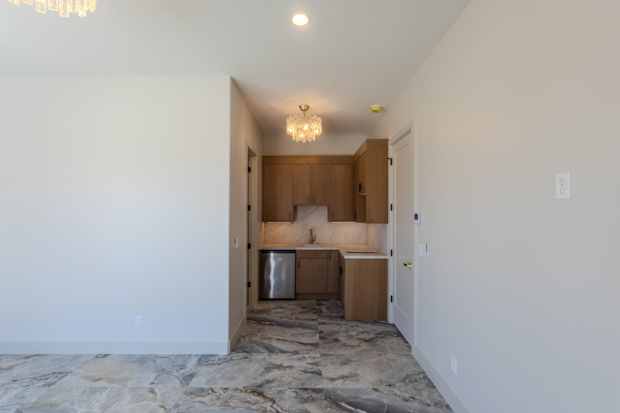 Wet bar featuring wood cabinetry, undermount sink, stainless steel beverage refrigerator, and tile flooring
