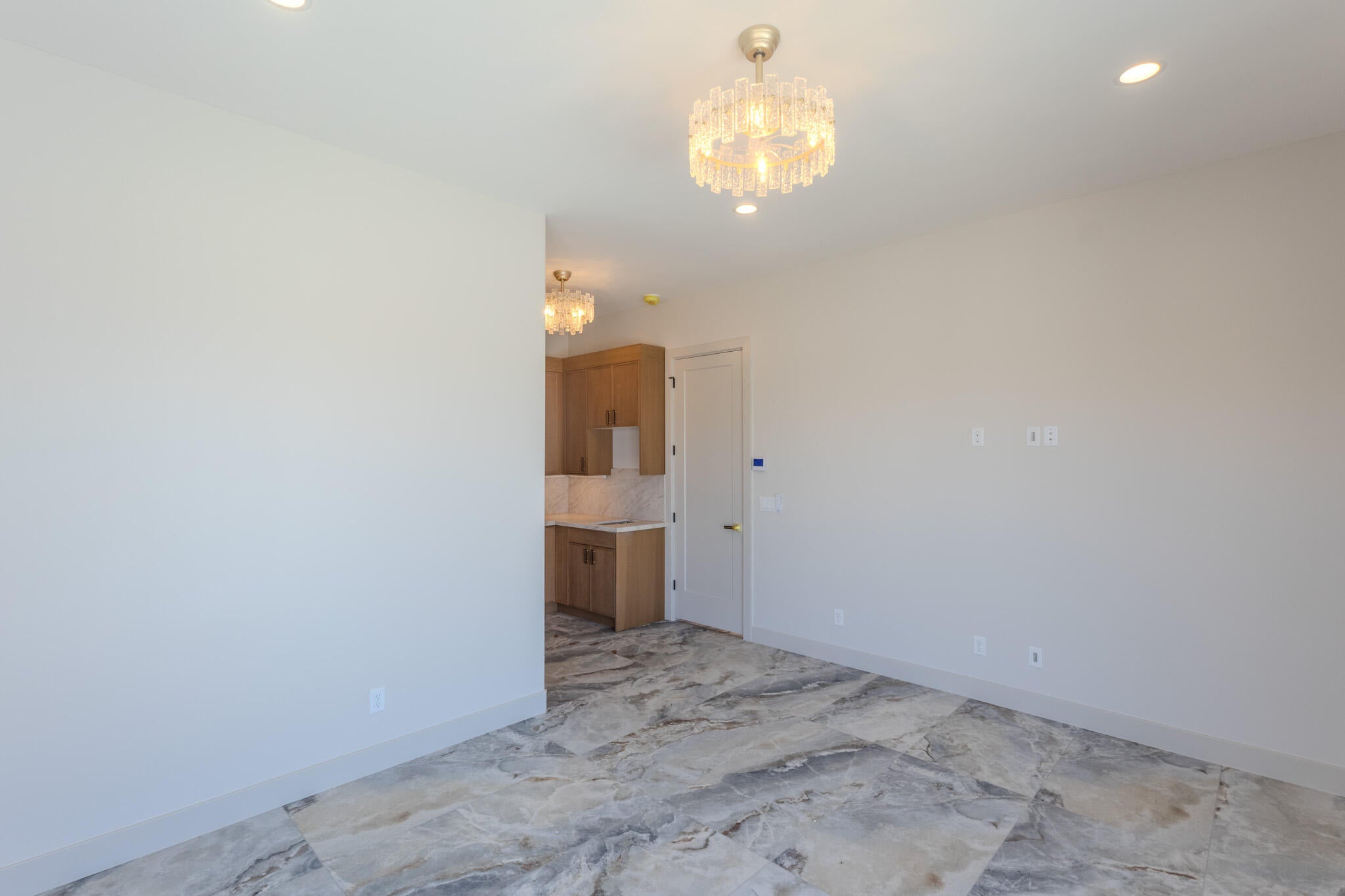 Spacious interior featuring marble-finish tile flooring, recessed lighting, and a decorative ceiling fixture
