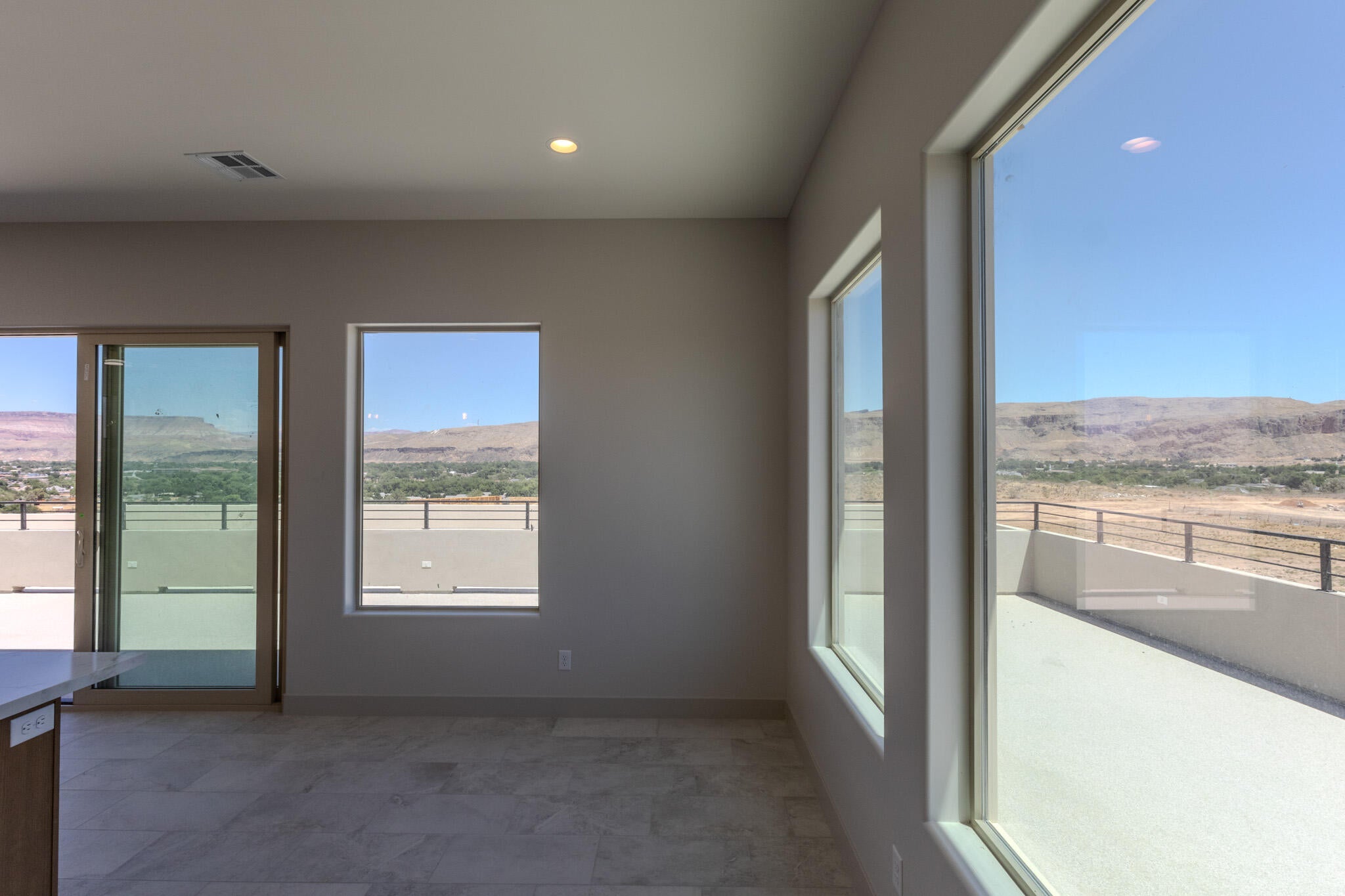 Spacious room featuring multiple large windows and a sliding glass door providing expansive mountain scenery
