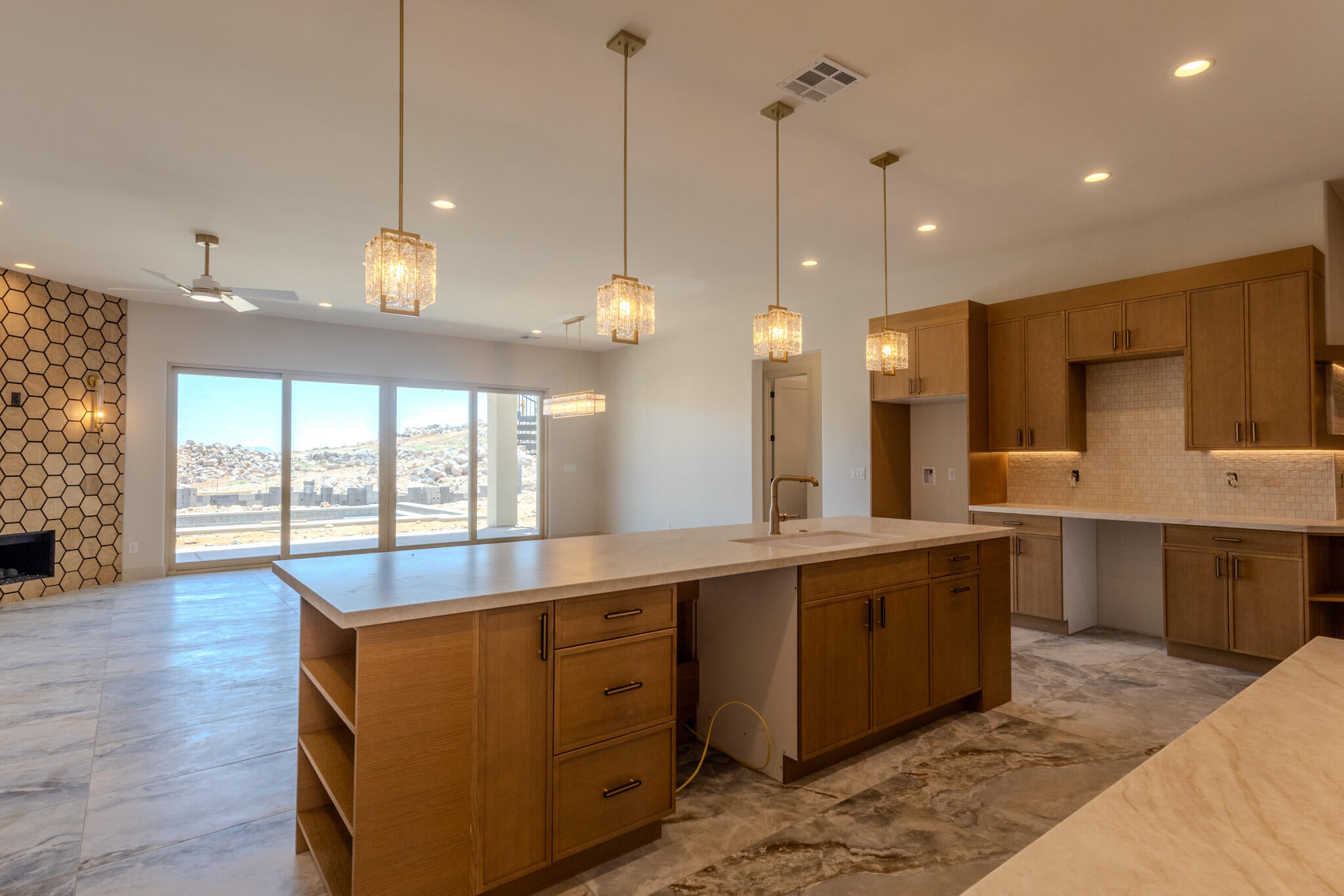 Kitchen featuring a large central island with integrated sink, light wood cabinetry, and a light-toned countertop