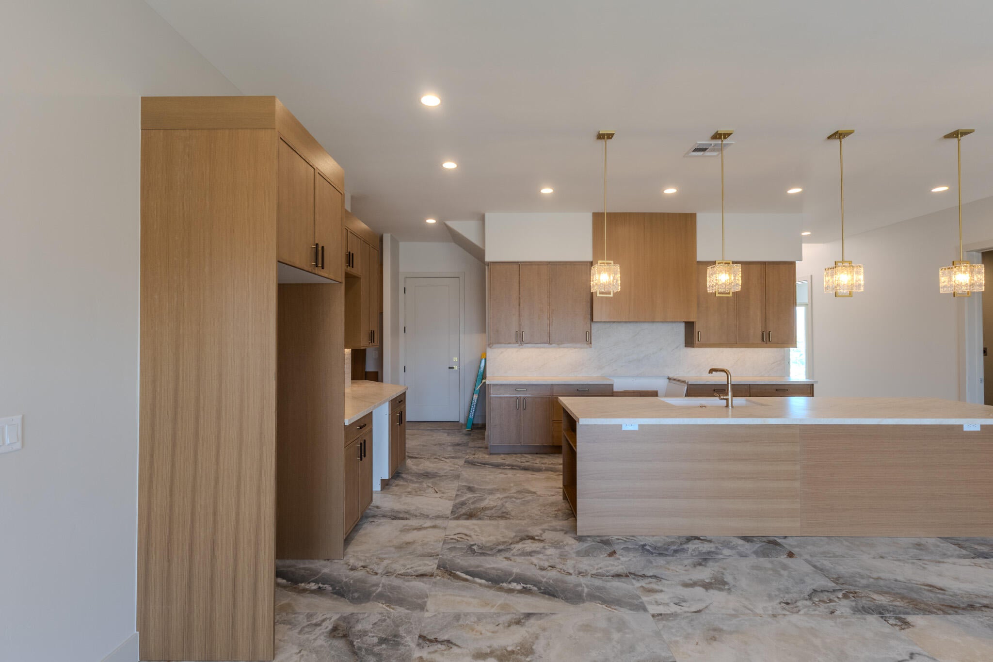 Contemporary kitchen featuring wood-finish cabinetry, a central island with an integrated sink, and an elegant tile backsplash