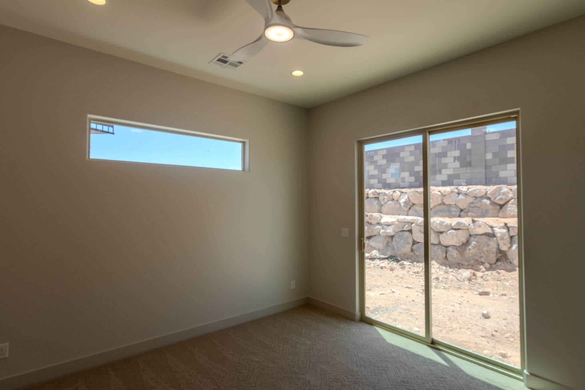 Spacious room featuring a ceiling fan with integrated lighting, recessed lighting, a horizontal window, and a sliding glass door