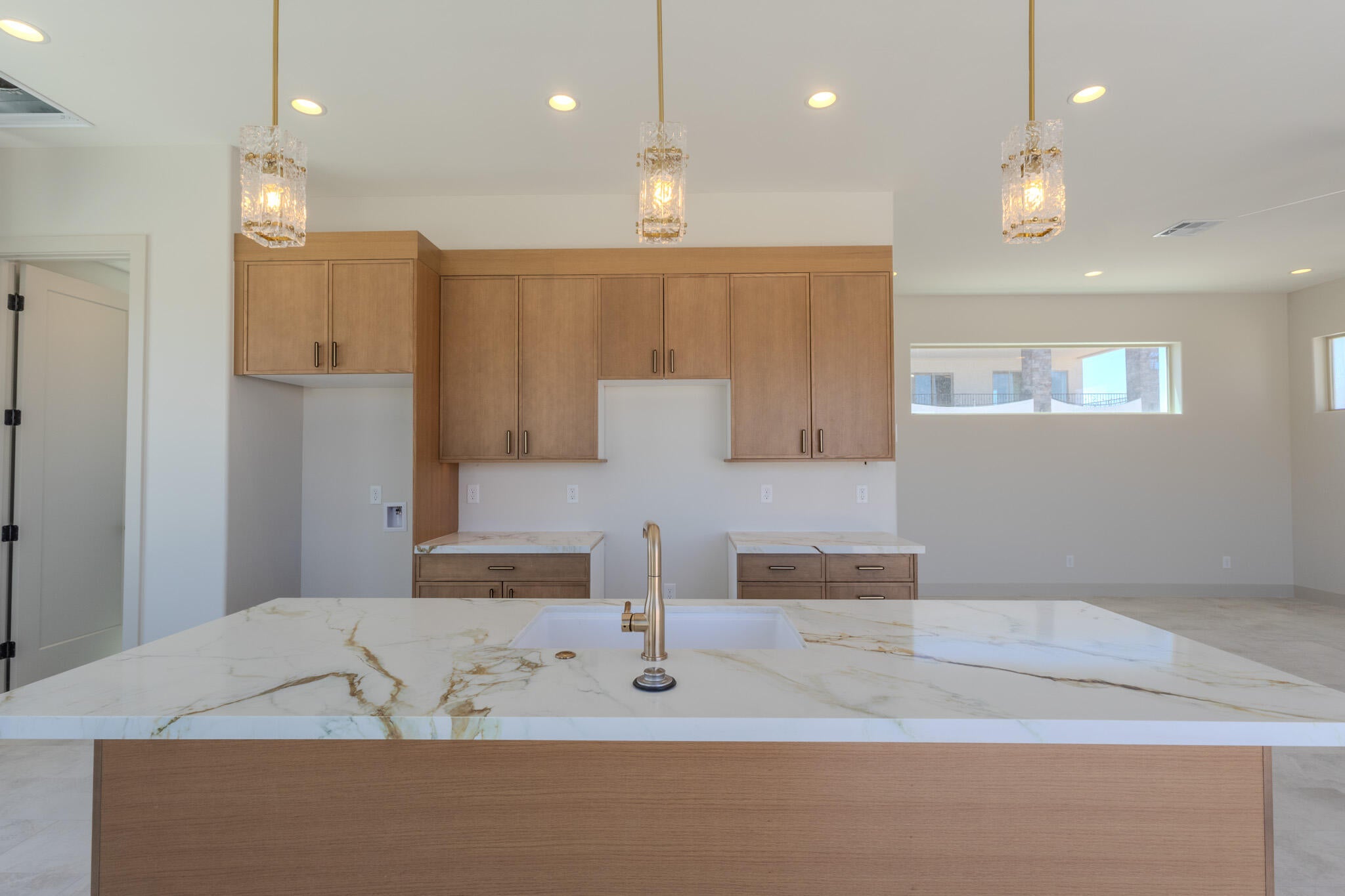 Kitchen island featuring a white countertop with gold veining, an undermount sink, and a gold-toned faucet
