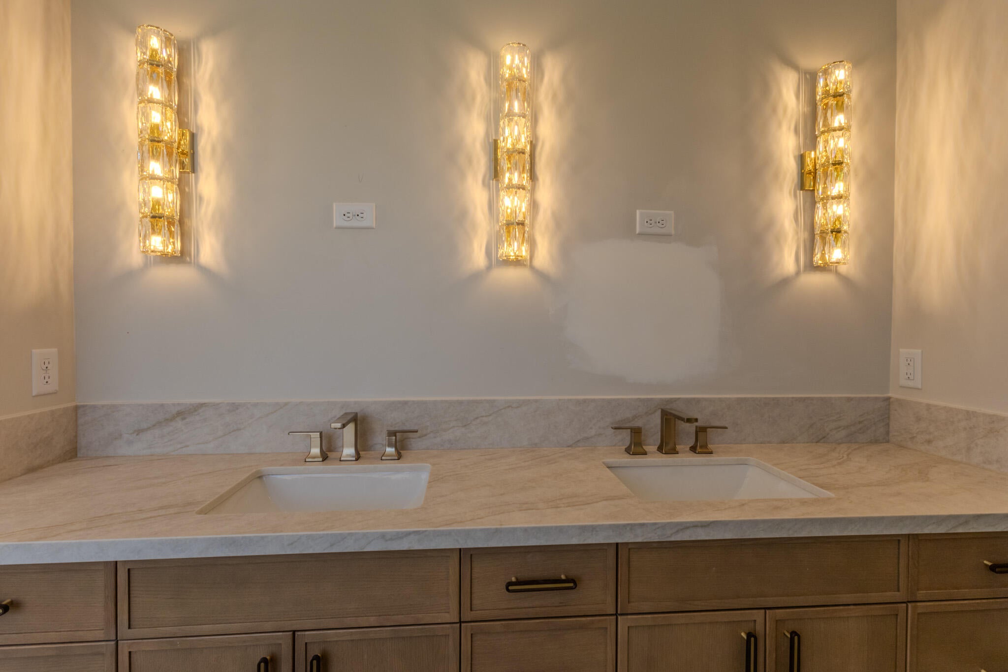 Dual vanity featuring undermount sinks, bronze faucets, and a light-toned countertop with a matching backsplash