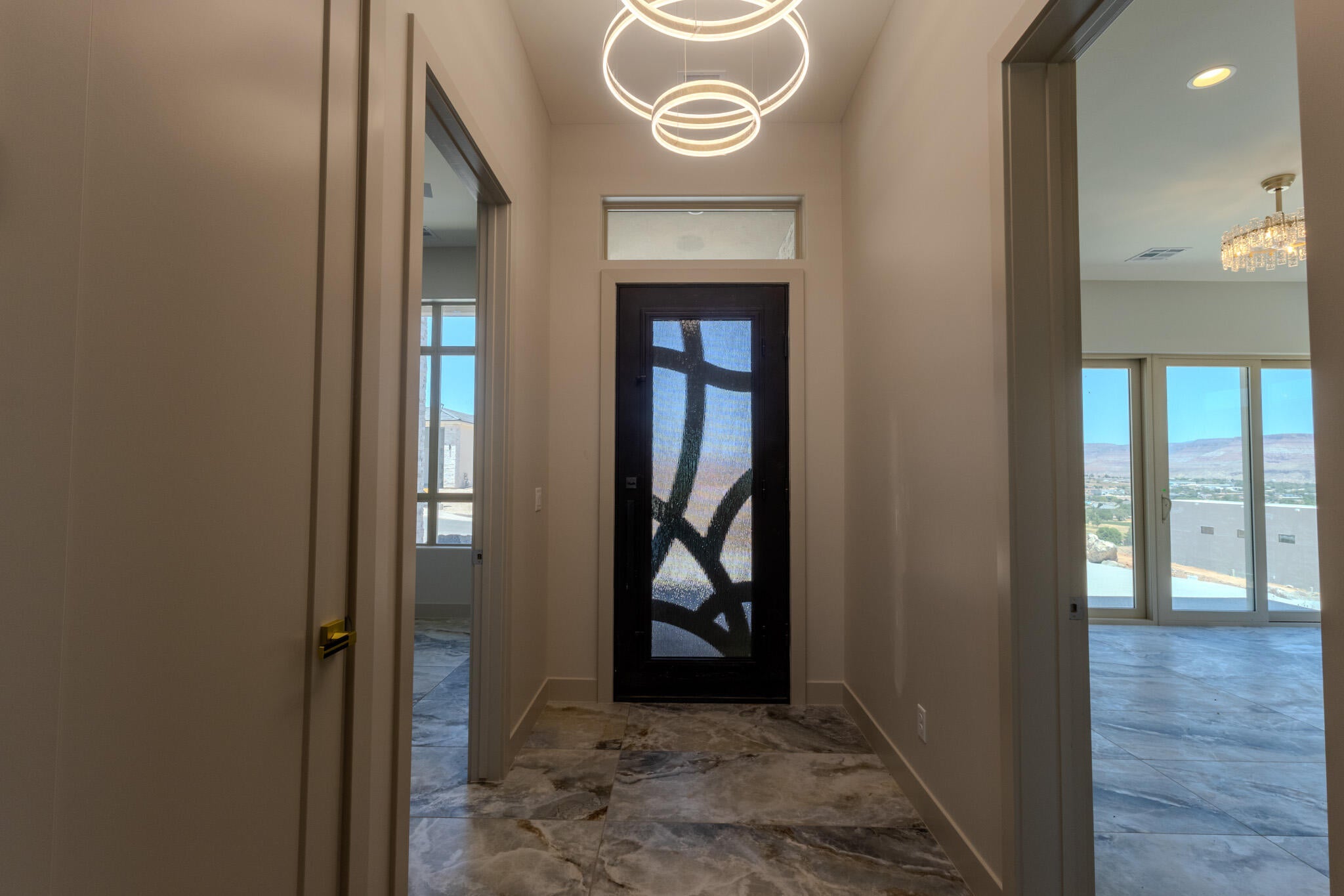 Entryway featuring a decorative front door with transom window, contemporary chandelier, and large format stone-finish tile flooring