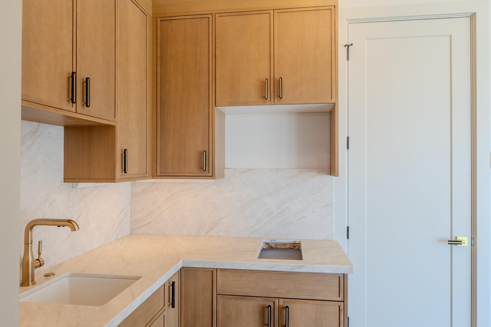 L-shaped countertop with an integrated sink, complemented by a brass-finish faucet and backsplash