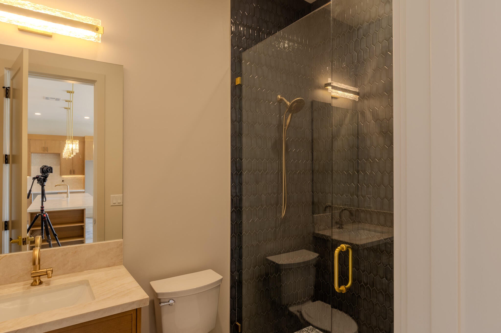 Bathroom featuring a glass-enclosed shower with dark hexagonal tile, a gold-toned showerhead, and a matching gold-toned handle
