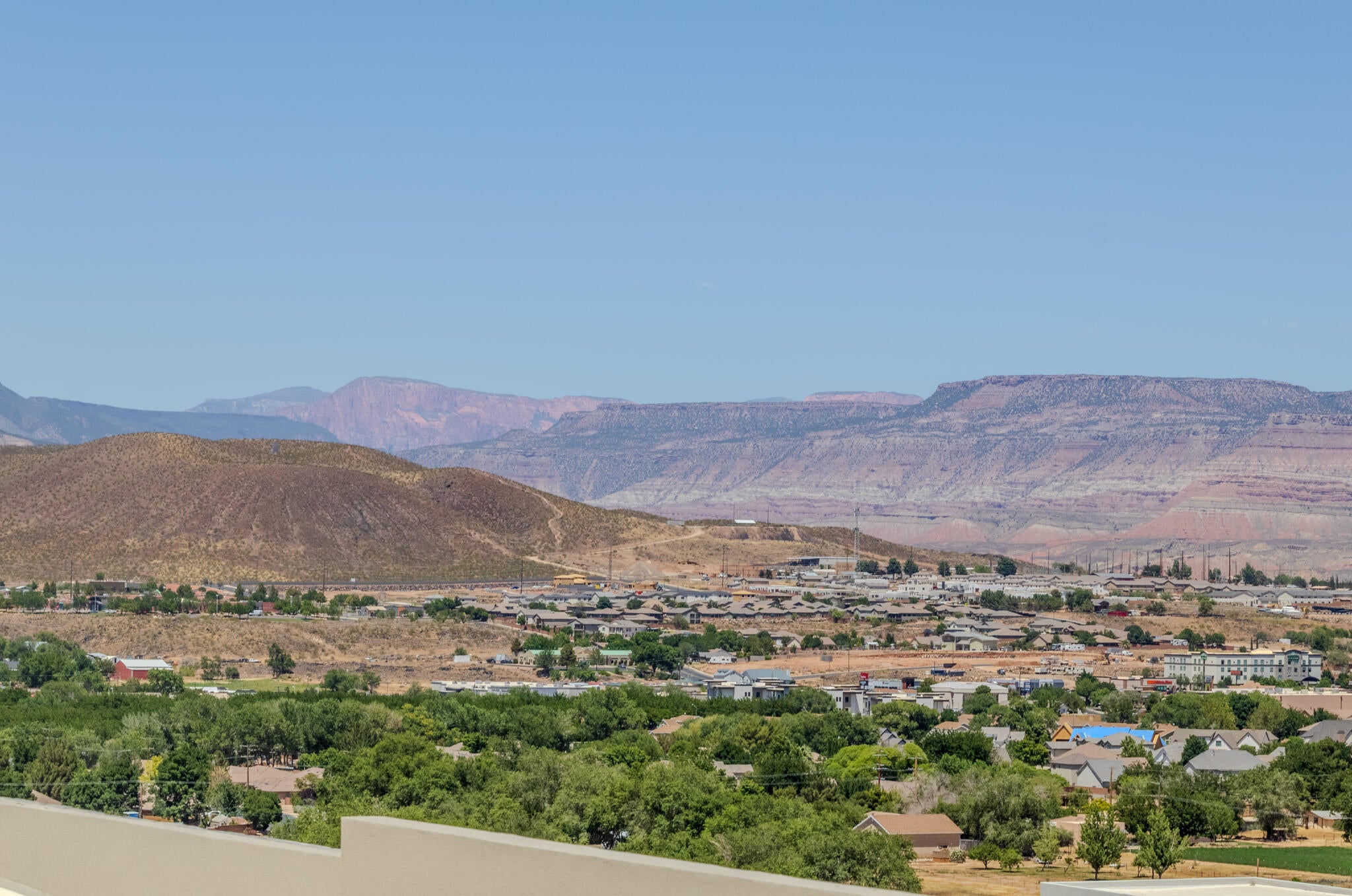 Expansive natural landscape featuring distant mountains and a valley with green foliage and residential development