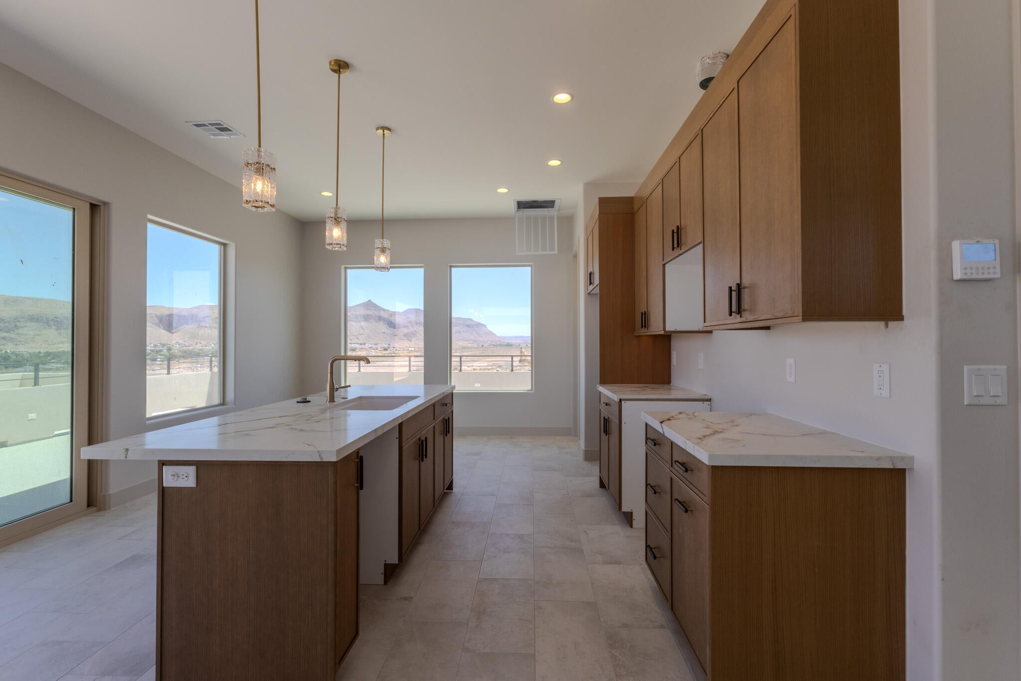 Kitchen featuring a central island with an undermount sink and a gold-tone faucet, complemented by three pendant lights