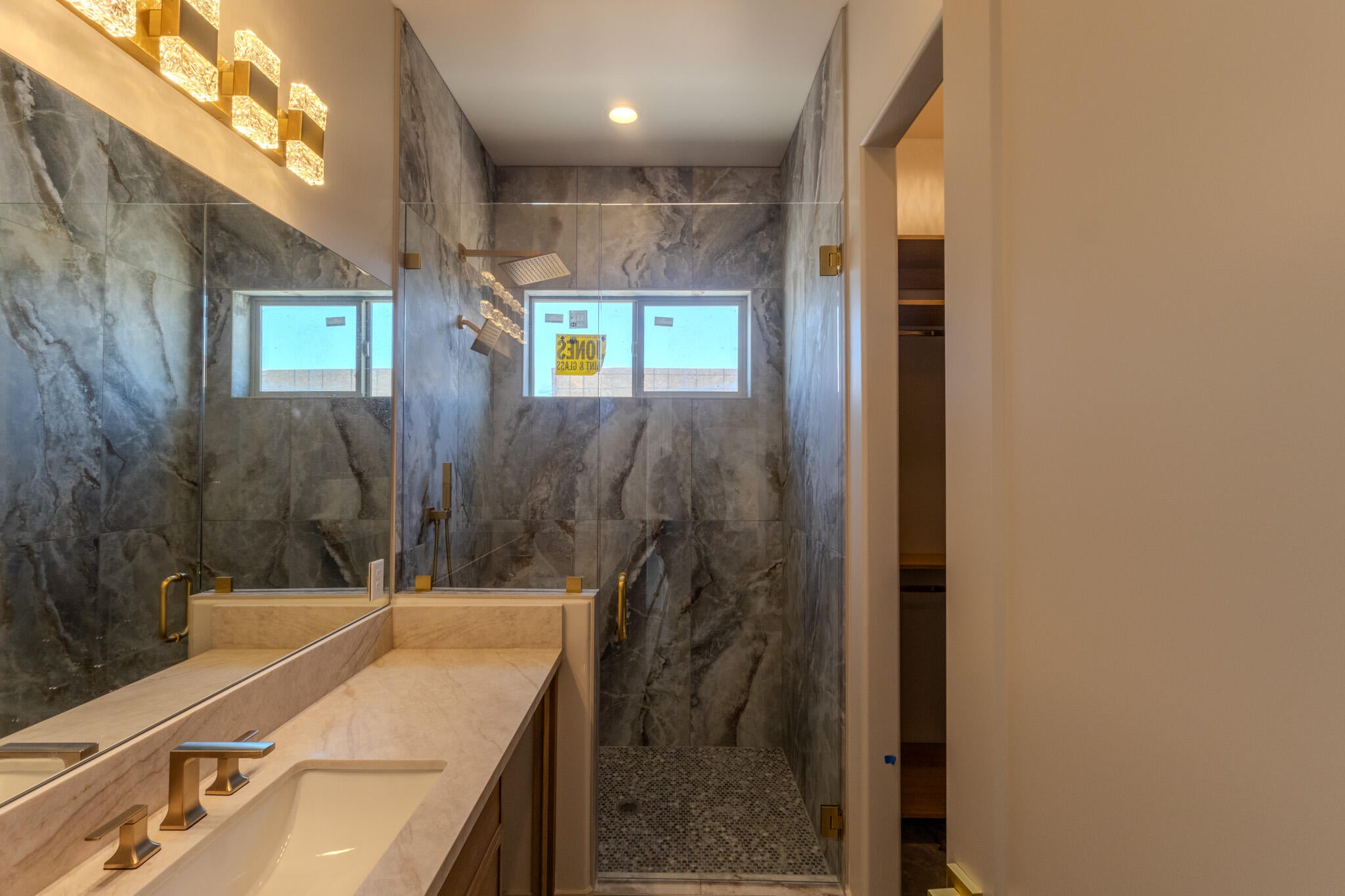 Contemporary bathroom featuring a spacious shower with dark marble-style tile walls, a rain showerhead, and a handheld shower fixture