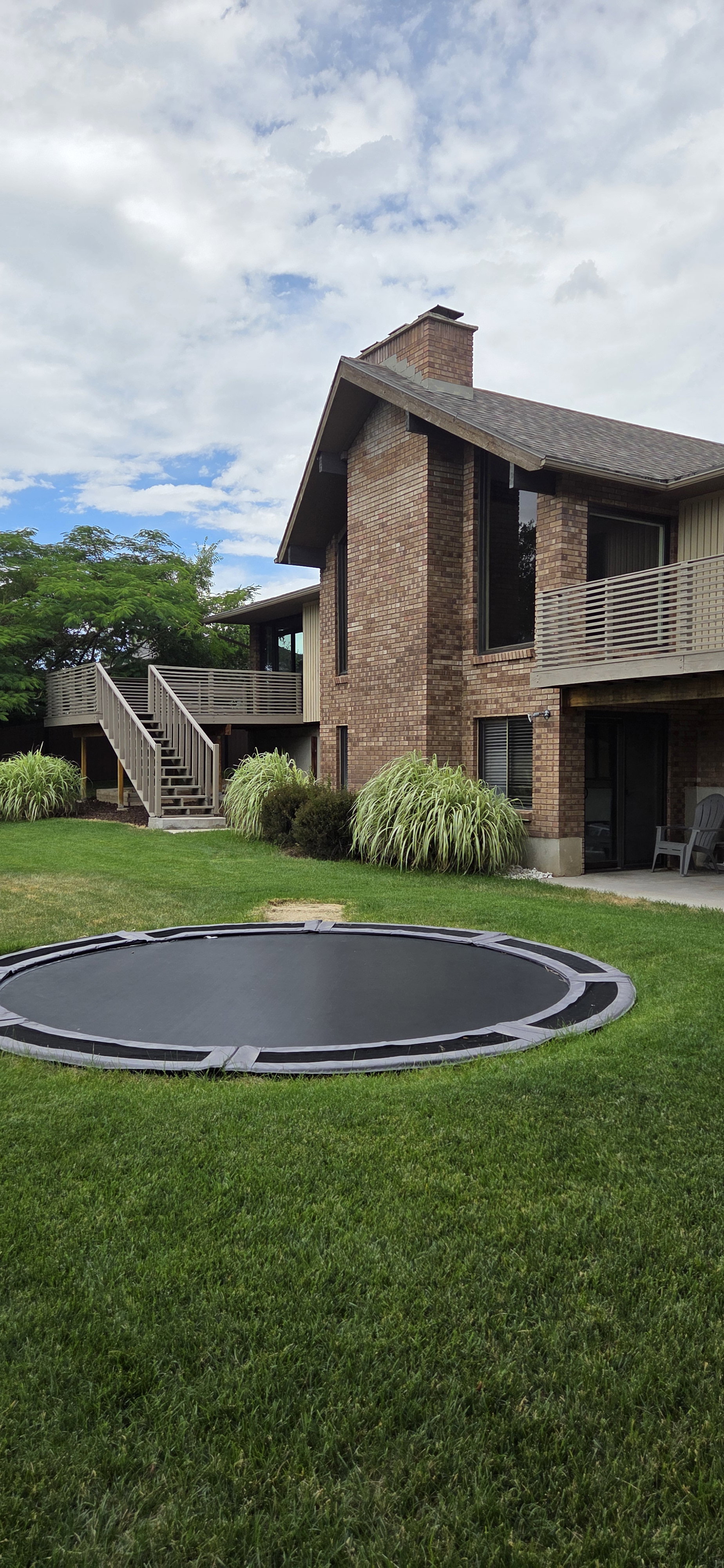 Expansive grassy yard featuring an in-ground trampoline