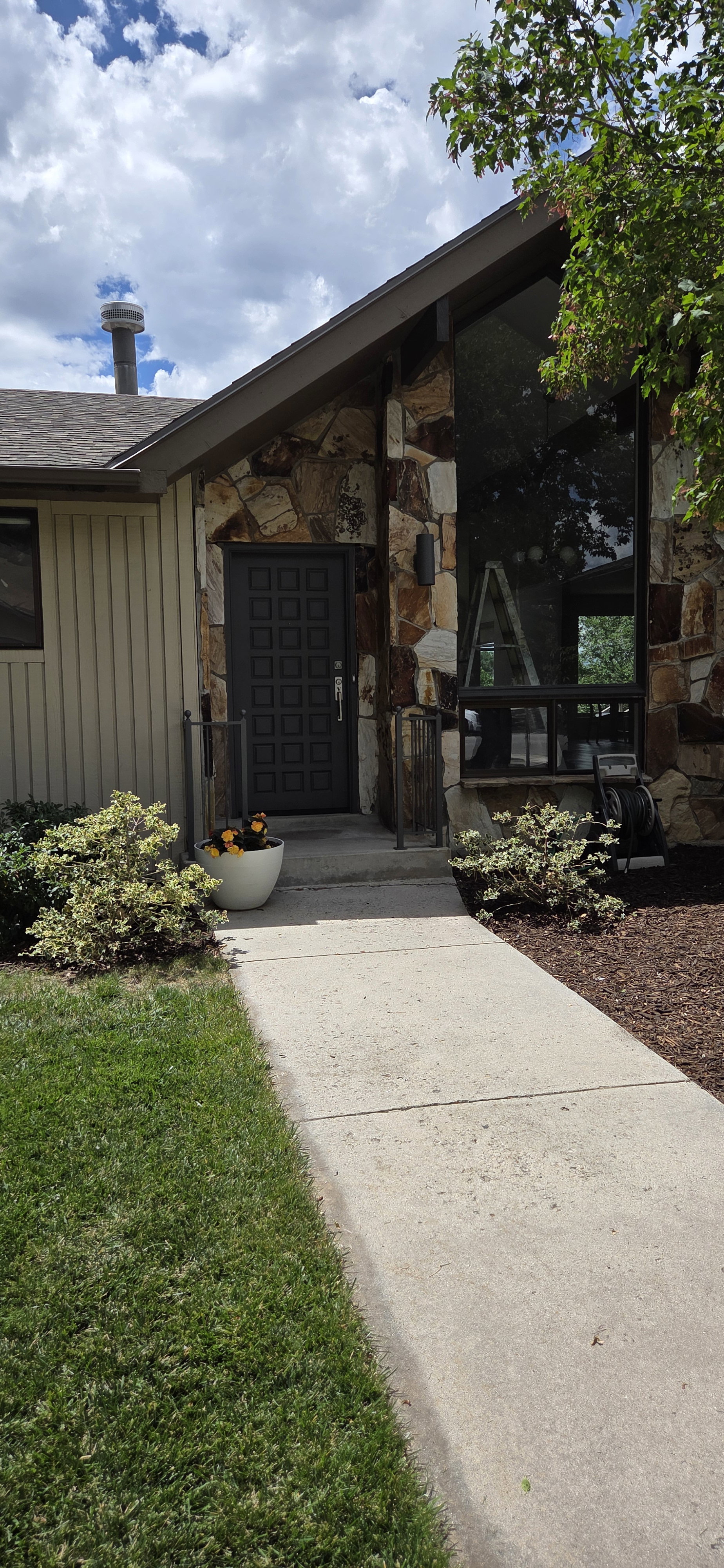 Stone facade entry featuring a dark paneled door and full-height windows
