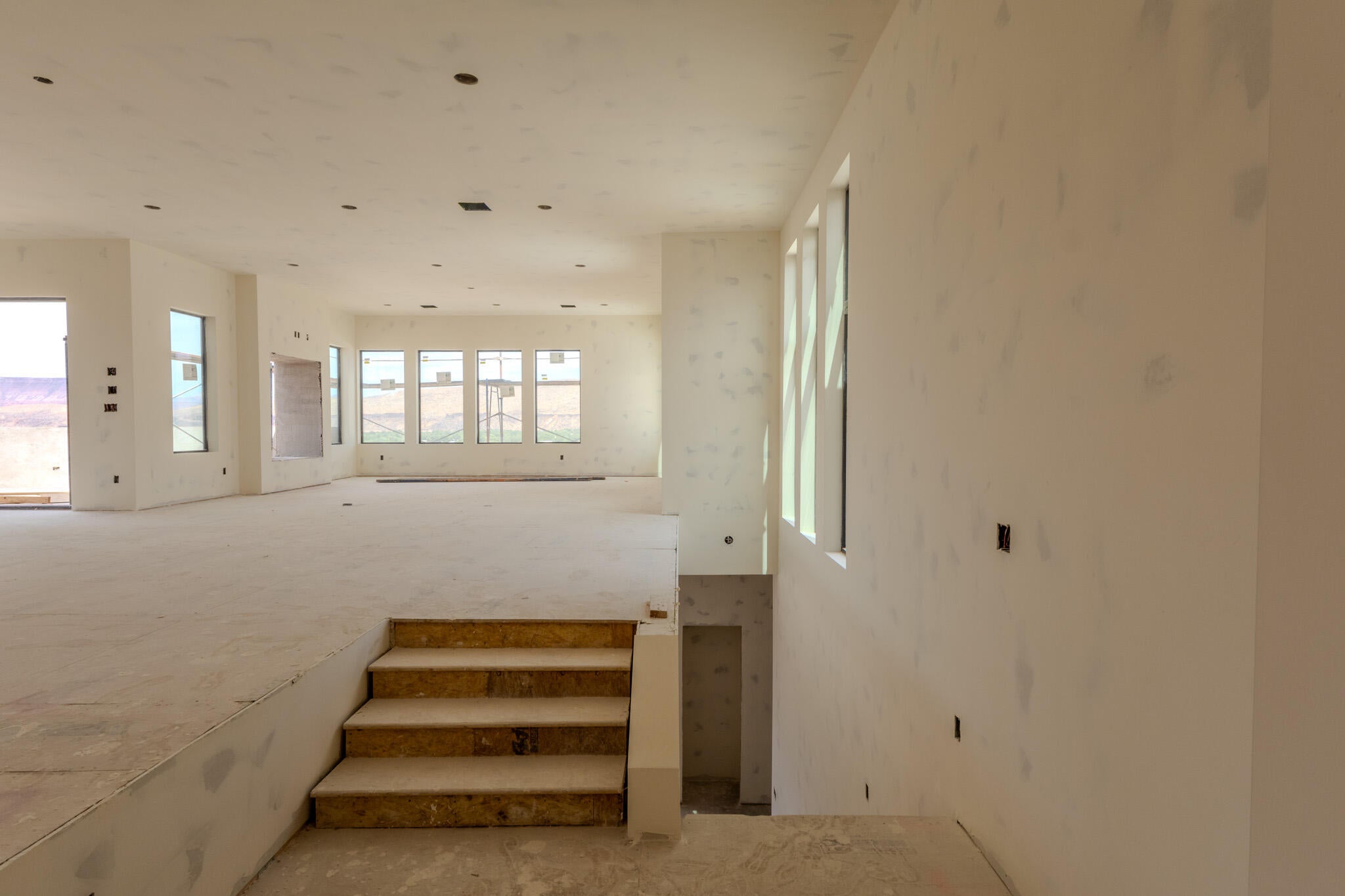 Open-concept interior featuring multiple large windows, recessed lighting, and a multi-level floor plan with visible stair access