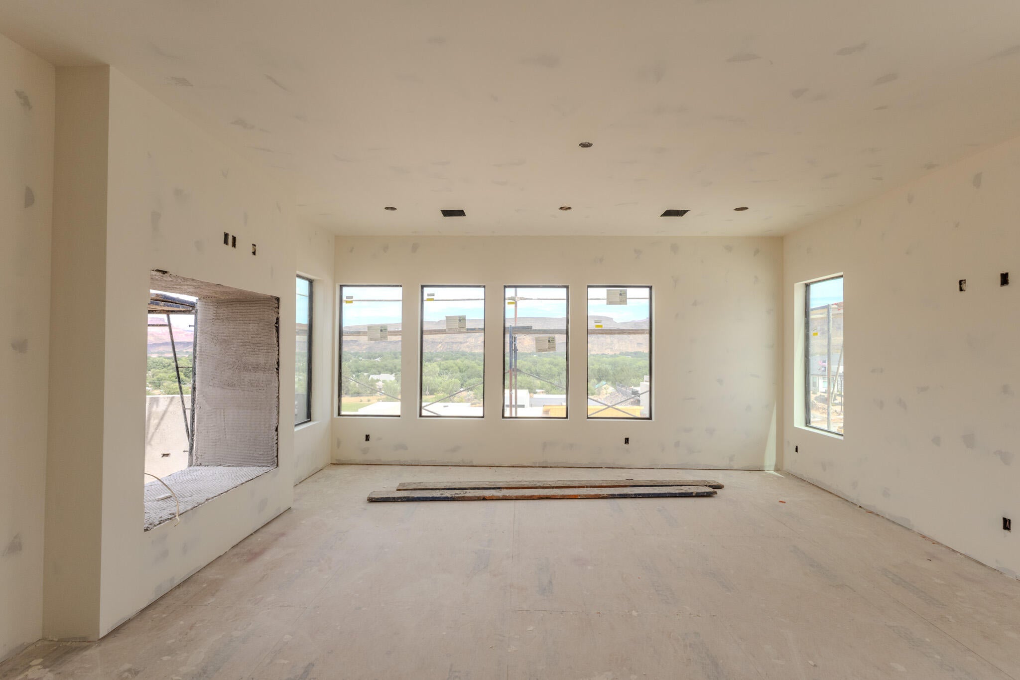 Spacious room featuring multiple rectangular windows, a large integrated cut-out, recessed ceiling lighting, and a neutral wall finish