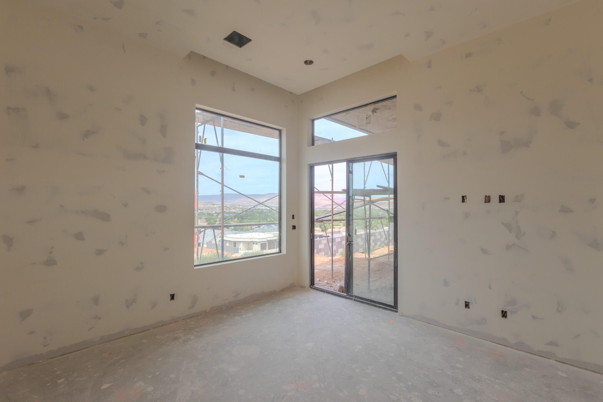 Spacious interior featuring large windows and a glass sliding door, offering exterior views