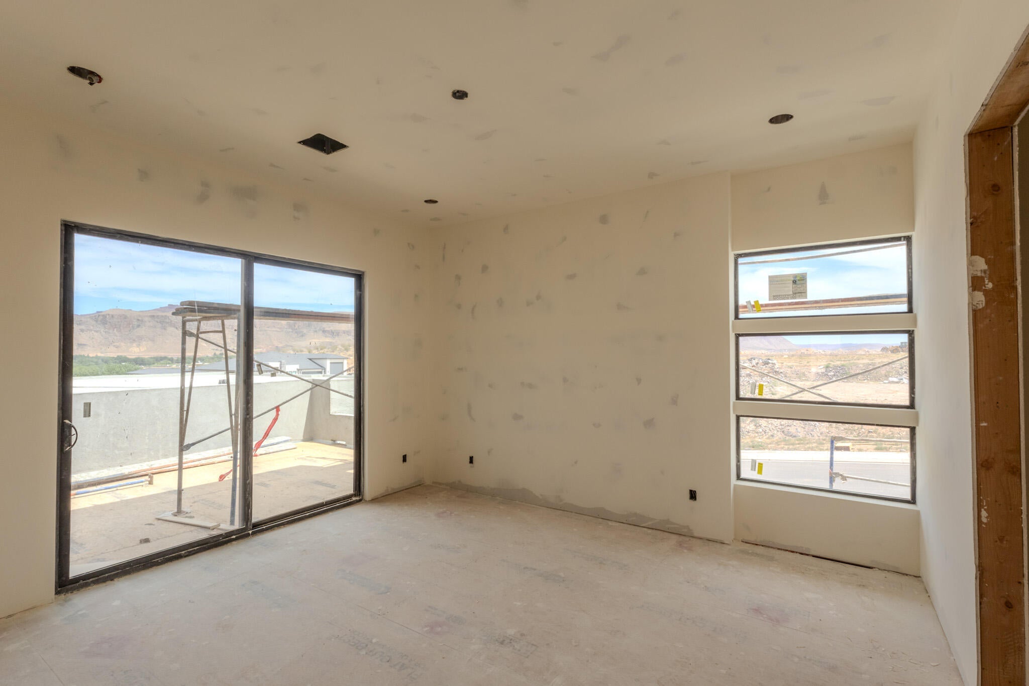 Spacious room featuring a large sliding glass door, three horizontal transom windows, recessed ceiling lighting, and rough-in wiring