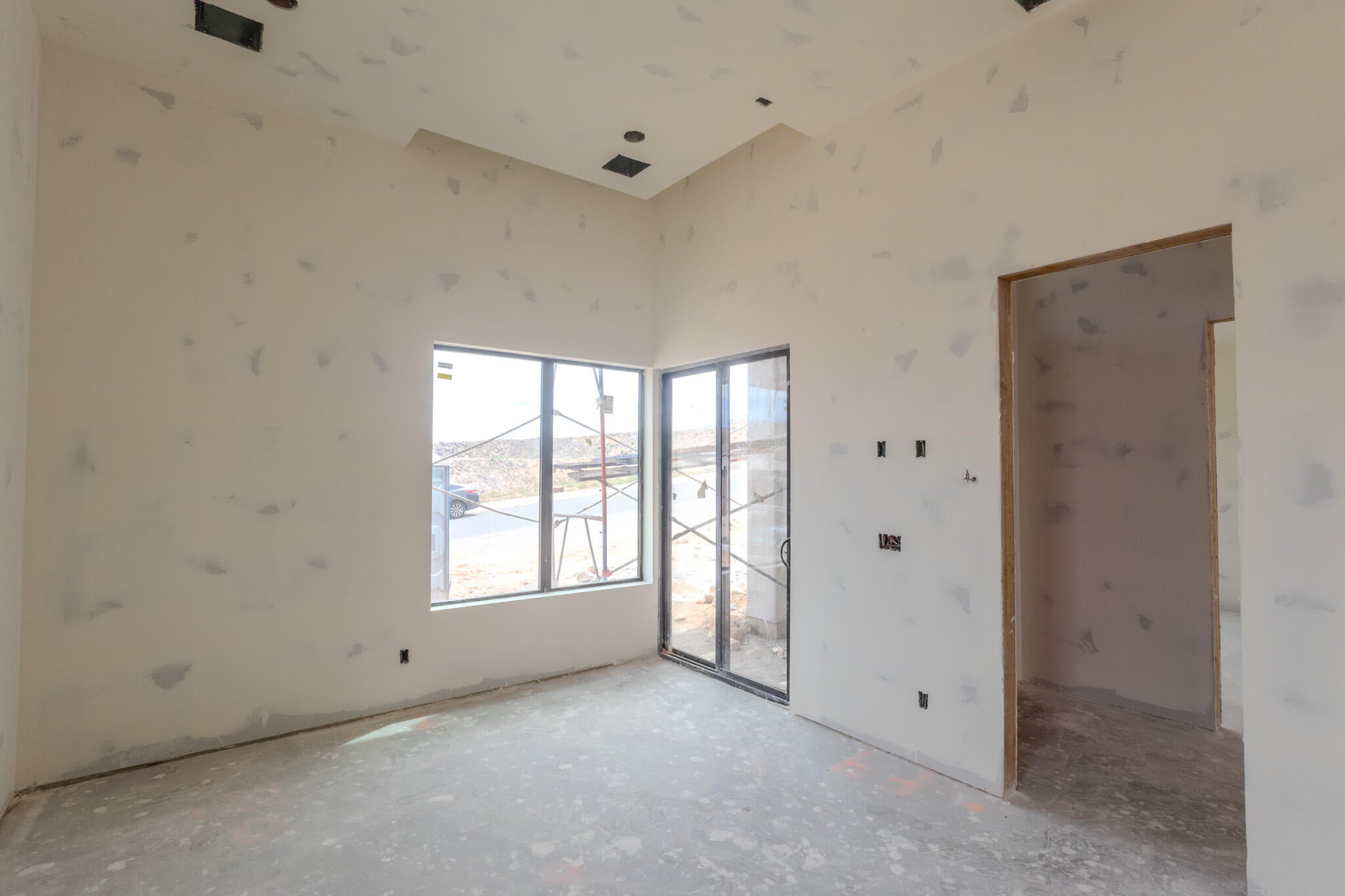 Interior room featuring a large window, sliding glass door, vaulted ceiling, and recessed lighting
