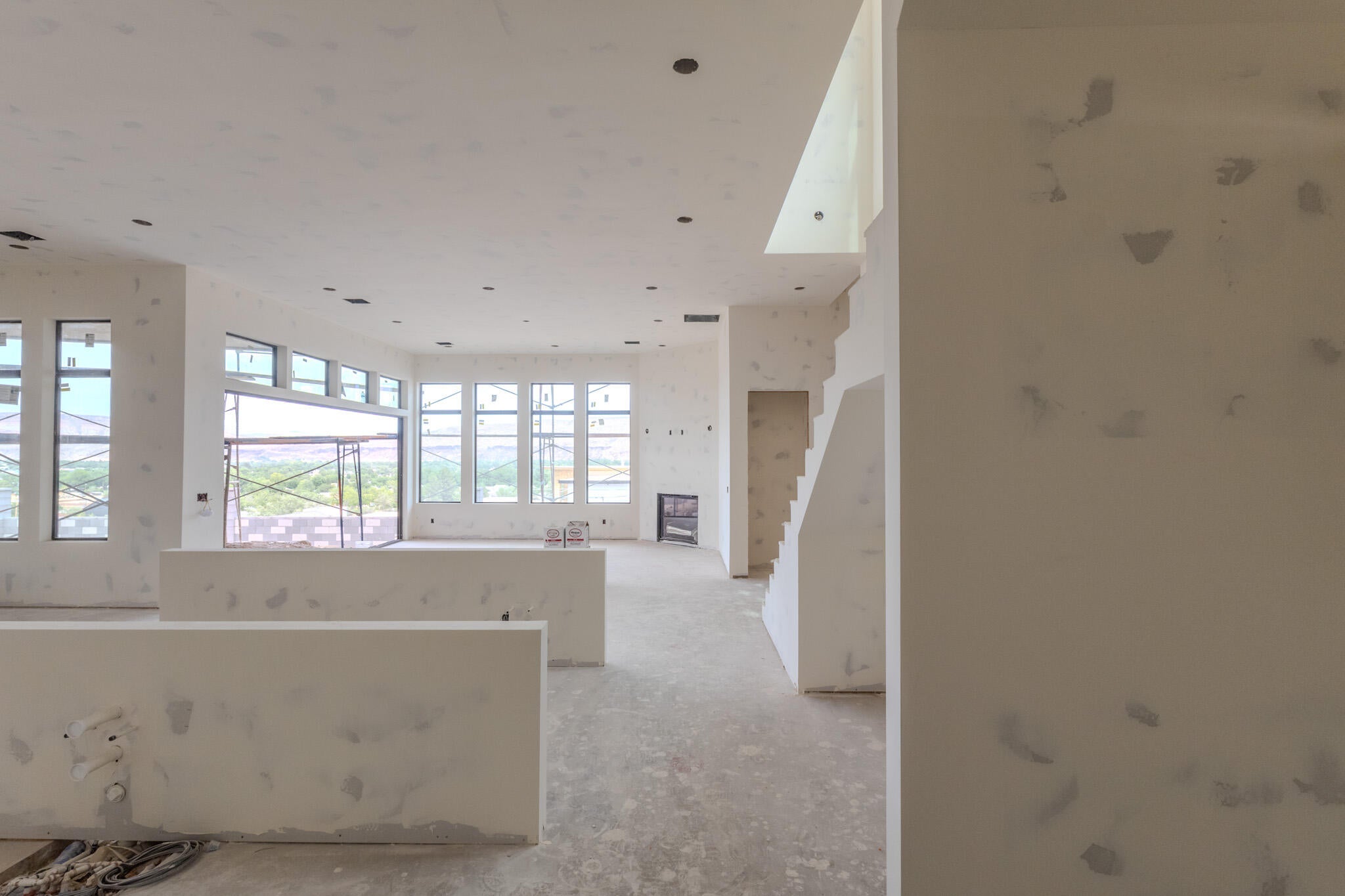 Open-concept interior featuring multiple windows, a prominent staircase, recessed lighting, and a fireplace