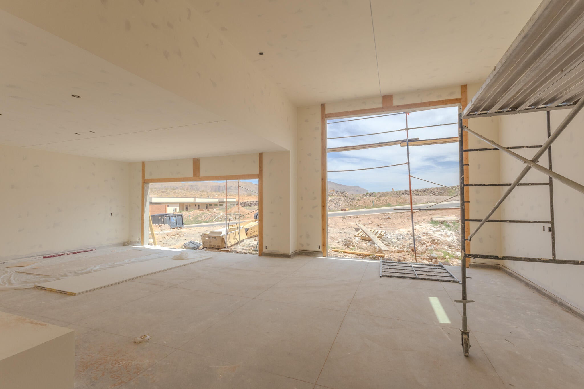 Expansive interior space featuring large window openings, unfinished walls, and a concrete floor