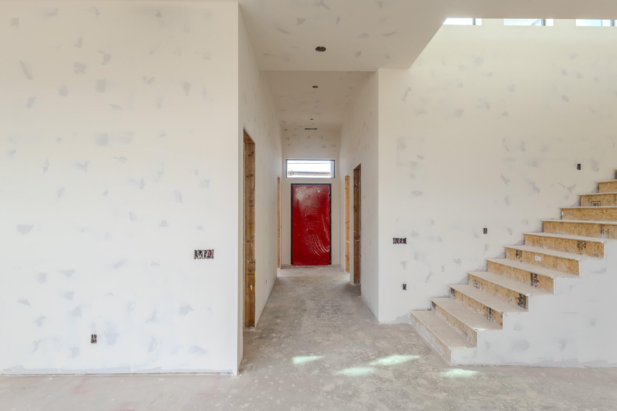 Open concept interior under construction featuring raw wood stair treads and an upper clerestory window
