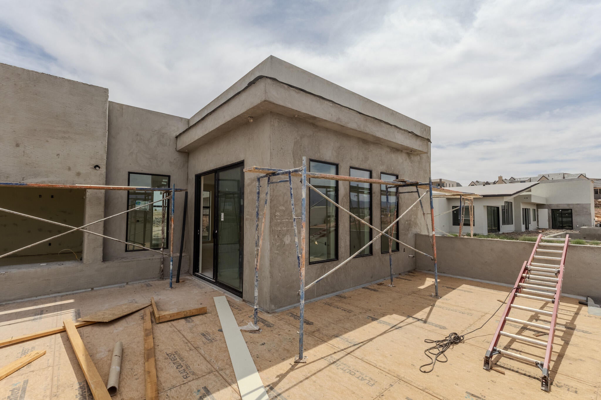 Contemporary stucco exterior with multiple black-framed windows and a sliding glass door