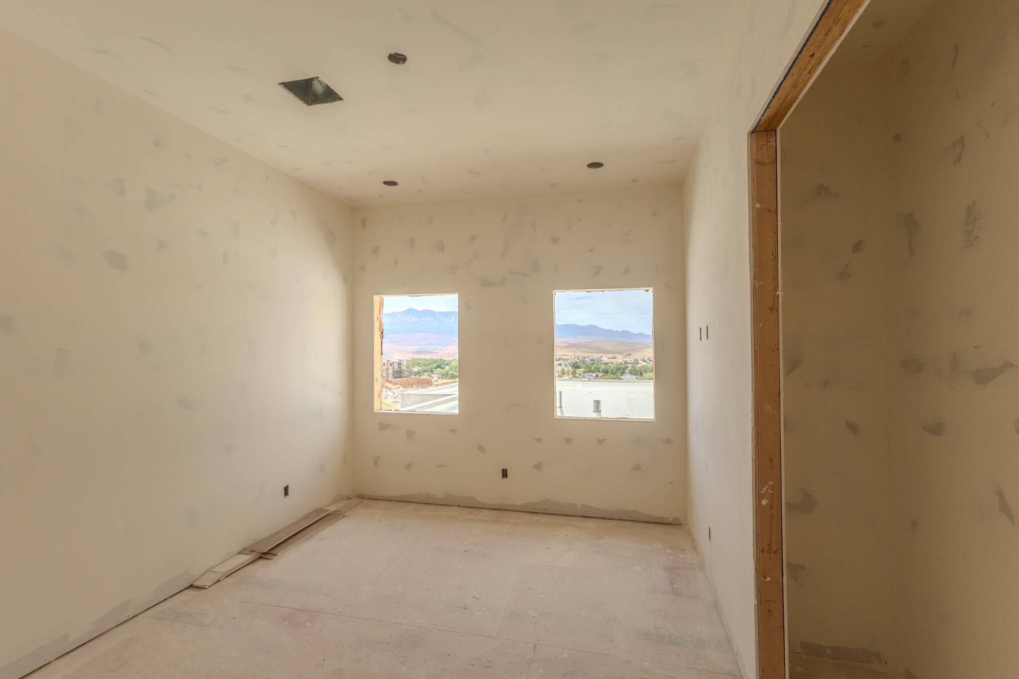 Unfinished interior space featuring two windows, recessed ceiling lighting, and an unfinished doorway, ready for customization