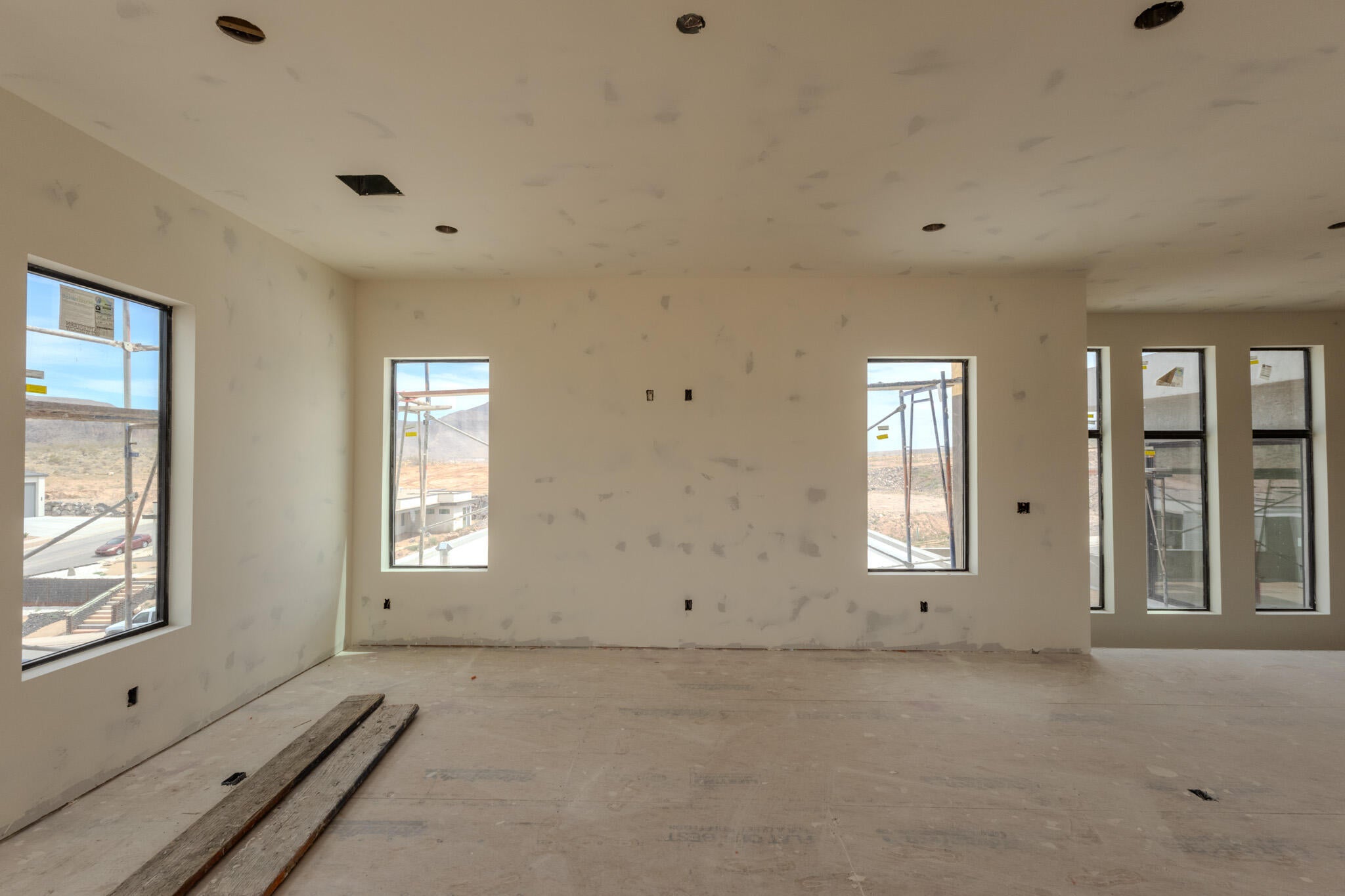 Expansive interior space featuring multiple large windows, recessed ceiling lighting, and a neutral wall palette