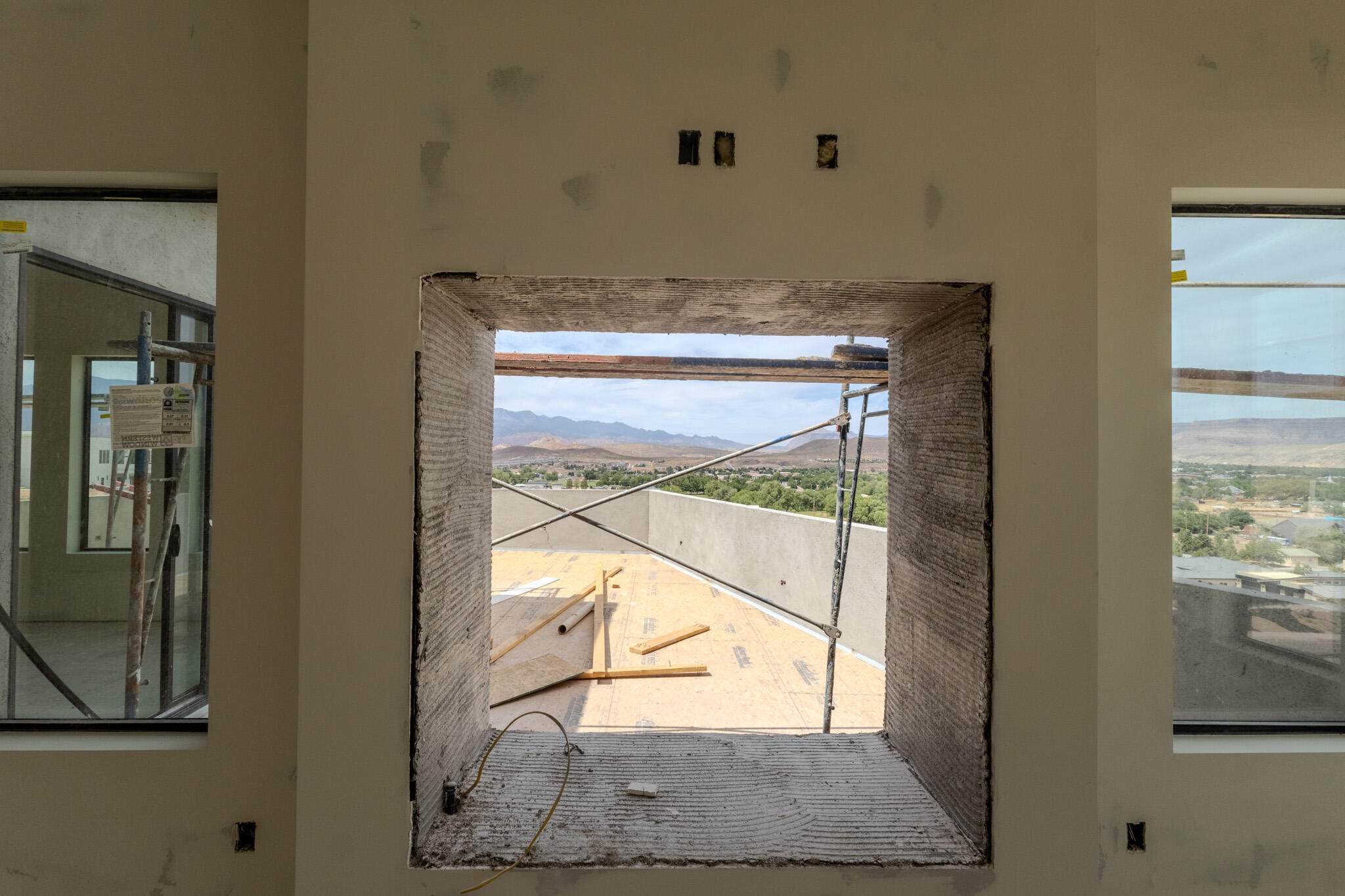 Expansive window openings showcasing distant mountains and a valley landscape