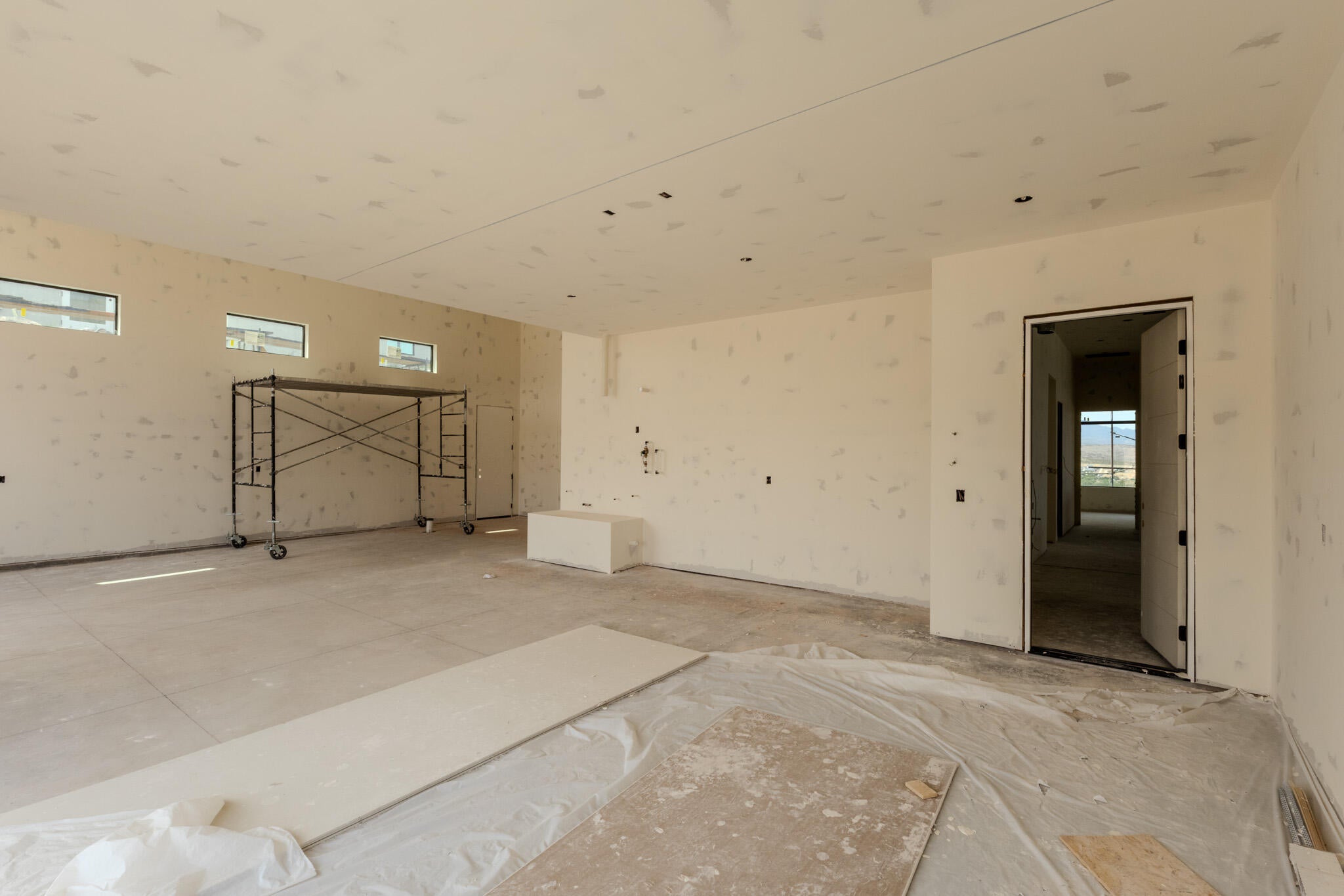 Spacious interior featuring multiple rectangular transom windows, a wide doorway, and concrete flooring