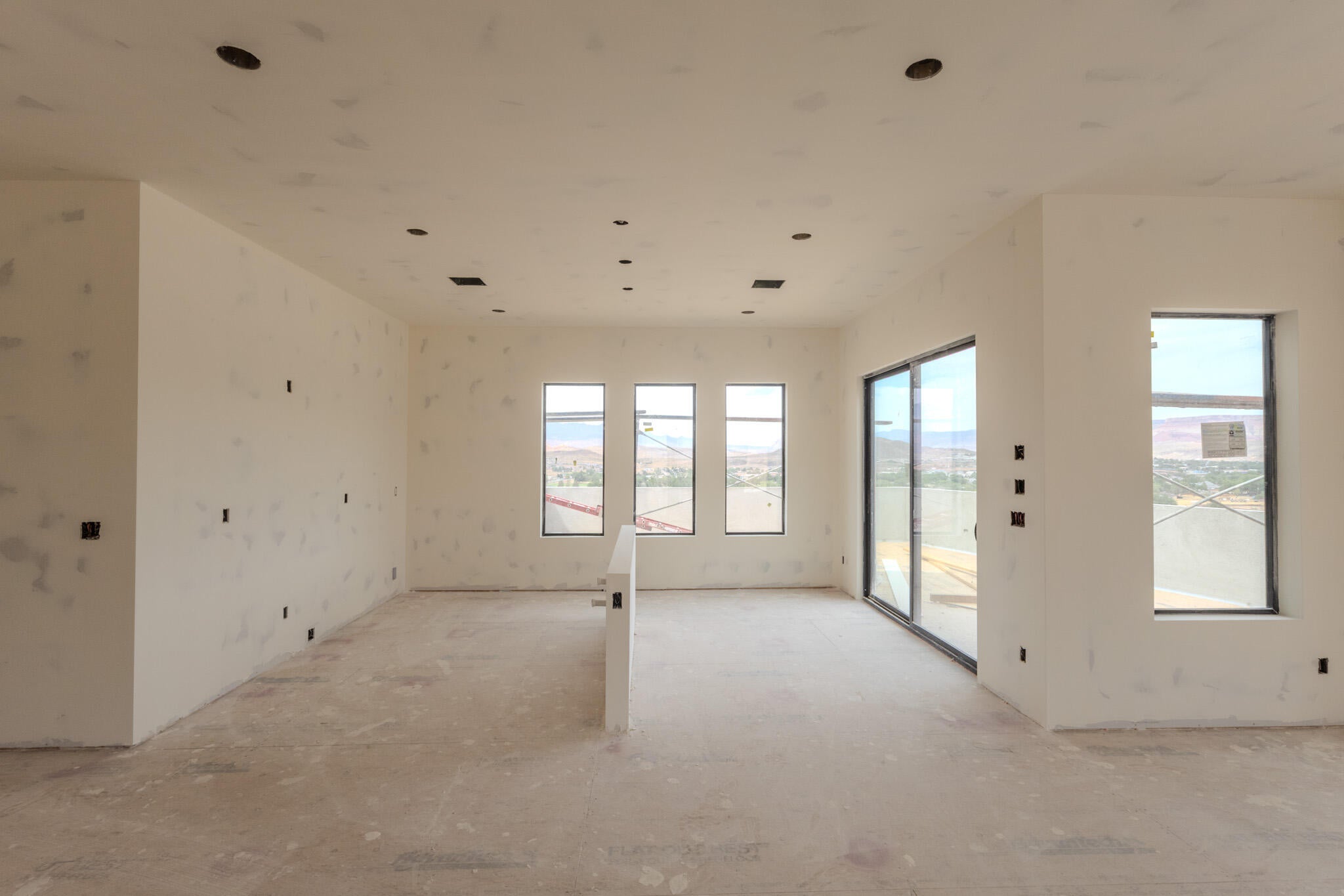 Expansive interior space featuring multiple large windows and a sliding glass door, providing abundant natural light