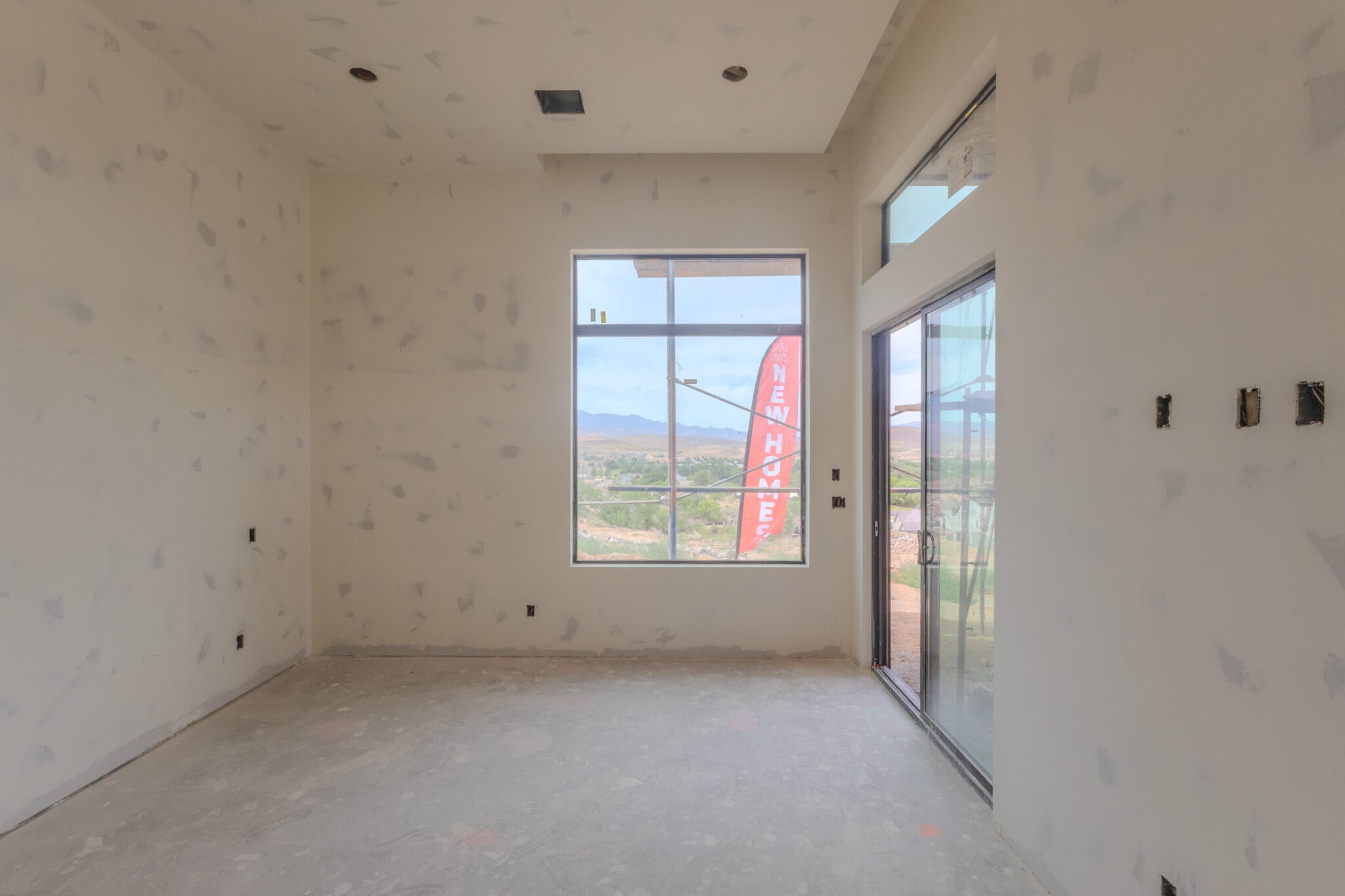 Spacious room with high ceilings, recessed lighting, a large picture window, and a sliding glass door