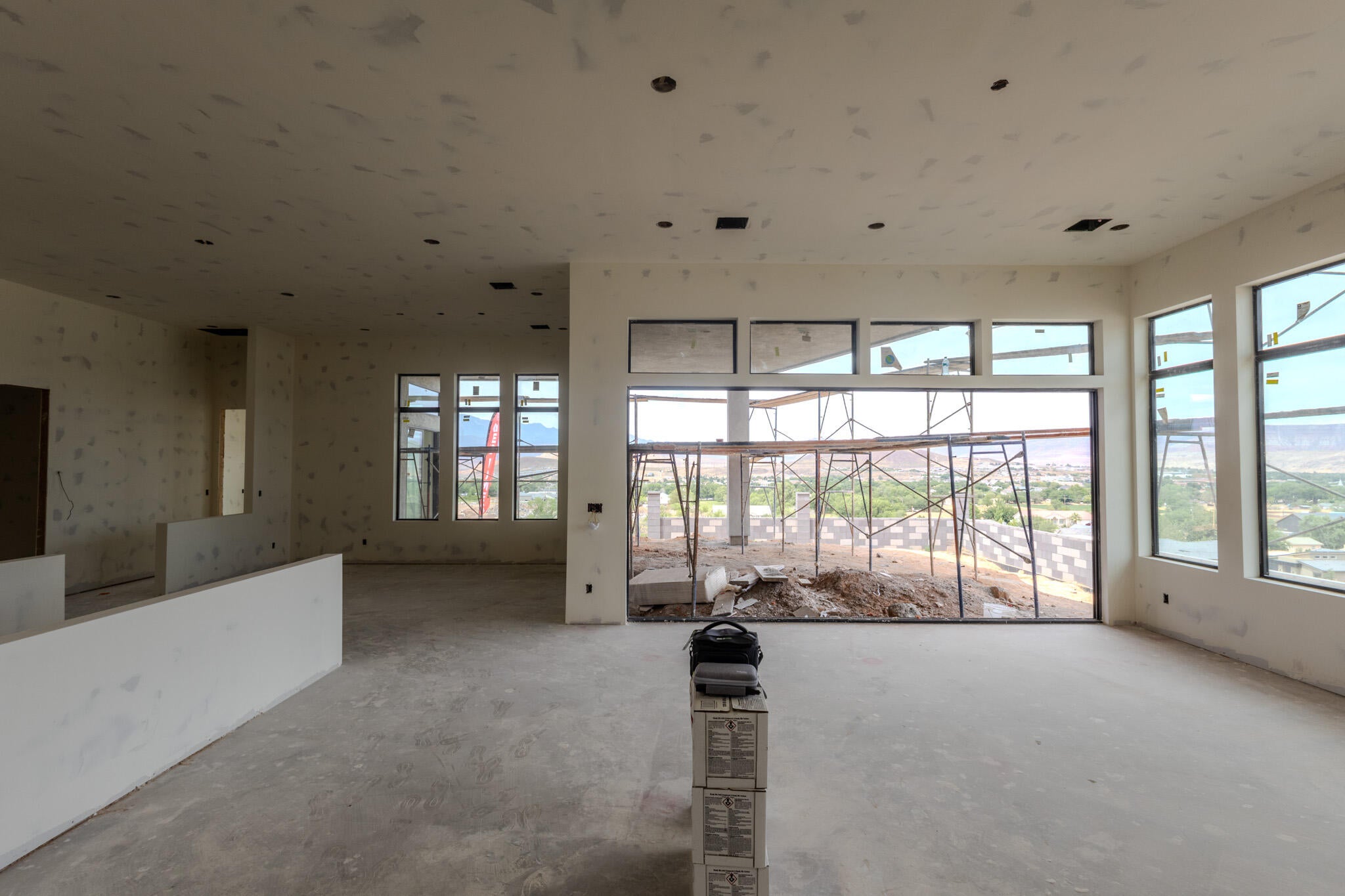 Expansive interior space featuring large windows, high ceilings, recessed lighting provisions, and unfinished concrete flooring