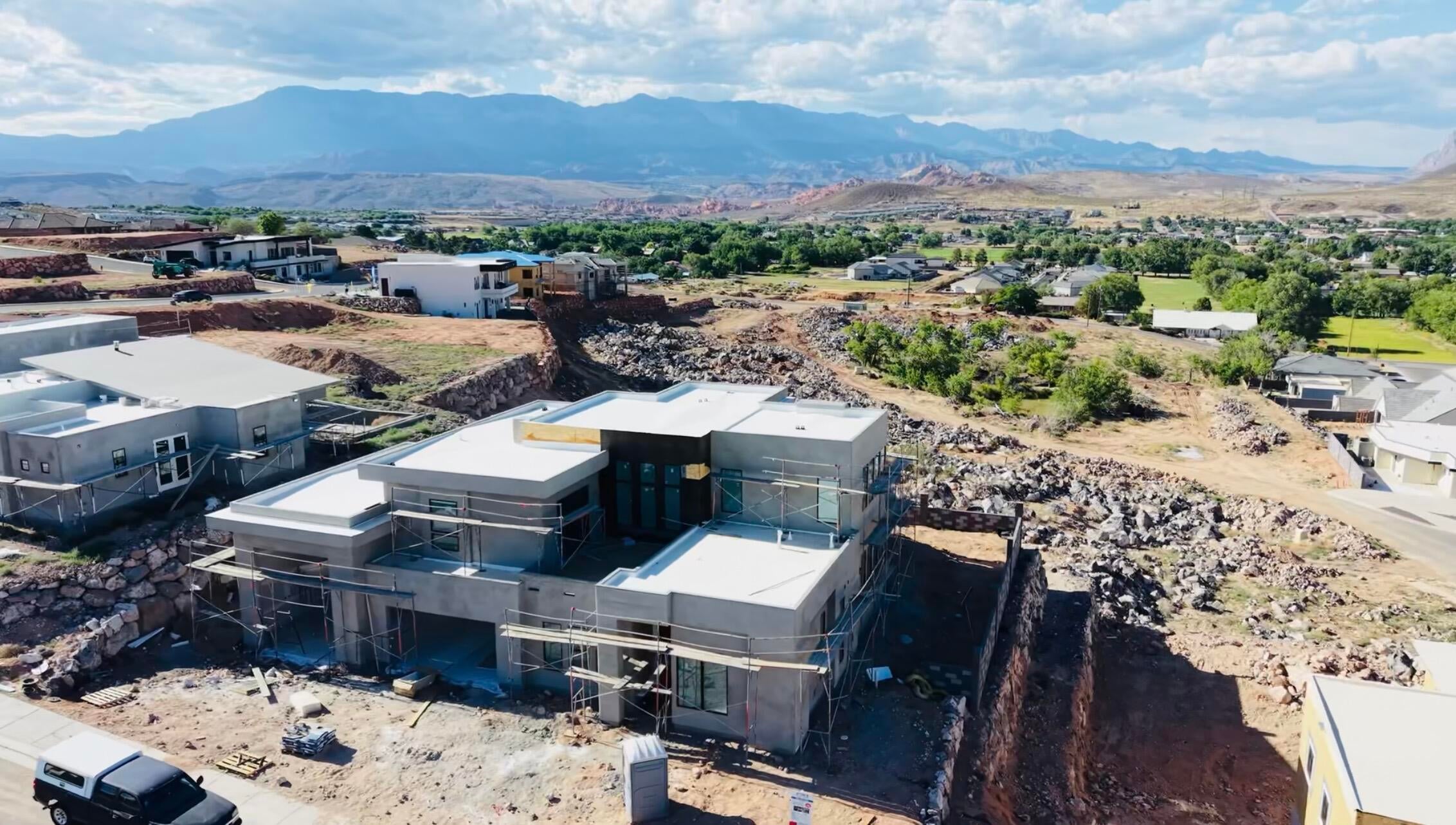 Contemporary home under construction featuring a flat roofline, multi-pane windows, and a stucco exterior