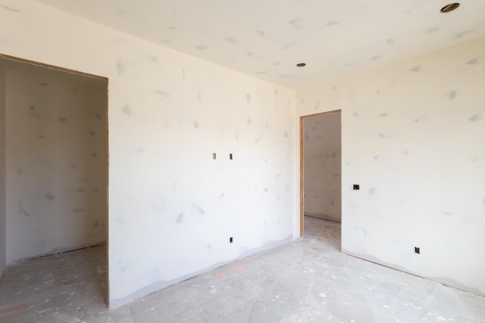 Unfinished interior space with neutral walls, multiple doorways, and recessed lighting openings