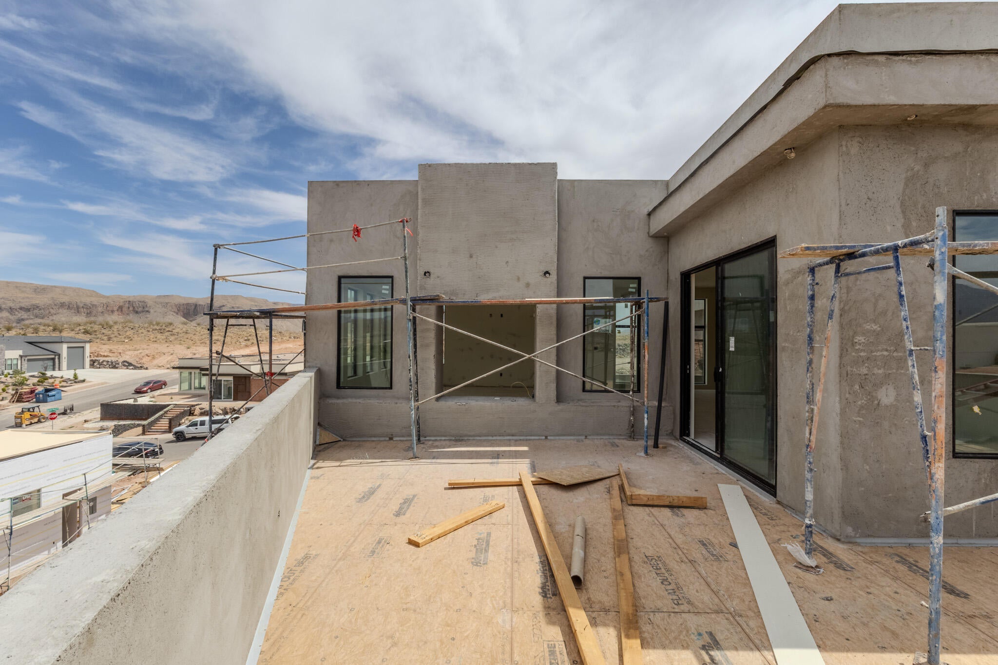 Rooftop deck featuring a concrete perimeter wall, a sliding glass door, and multiple windows with dark frames