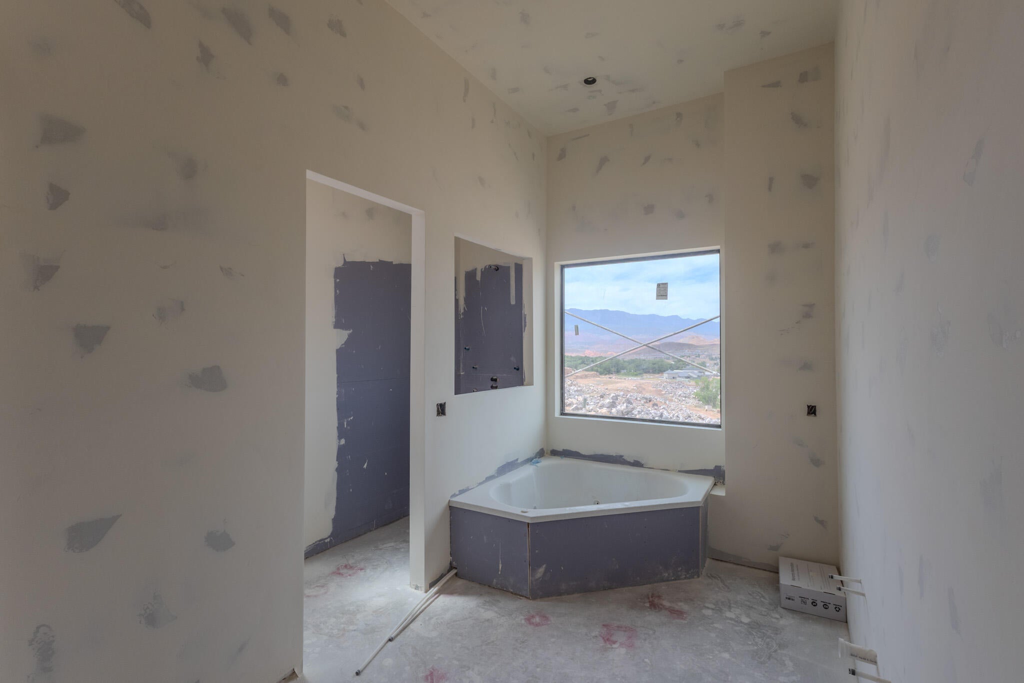 Corner soaking tub with a large window, offering mountain scenery