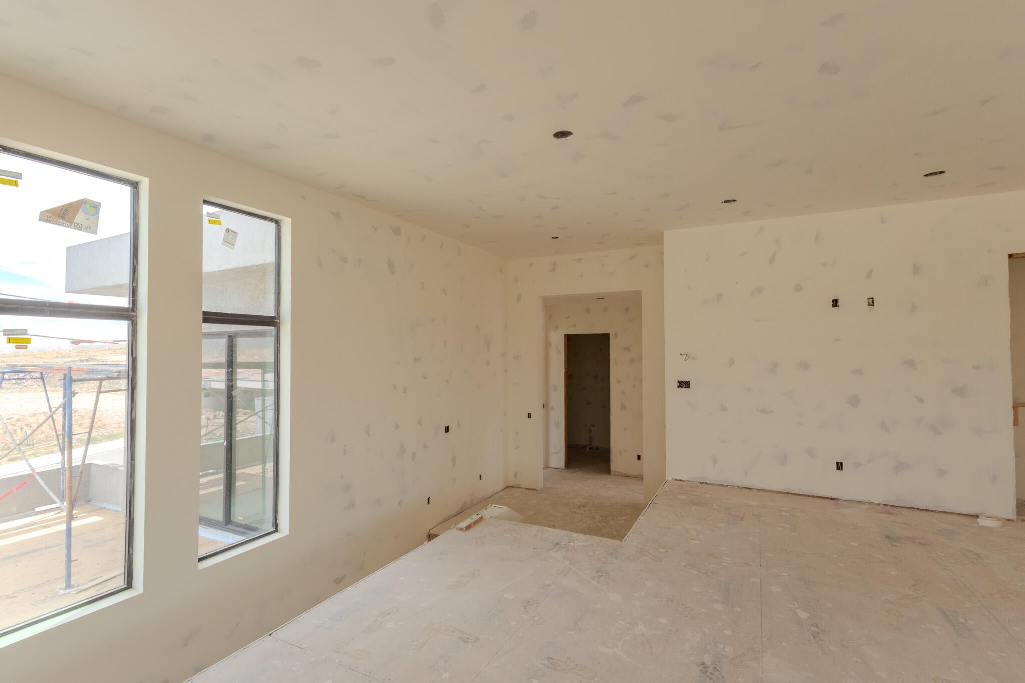 Open concept interior under construction, featuring multiple large windows, recessed ceiling lighting, and multiple electrical outlets