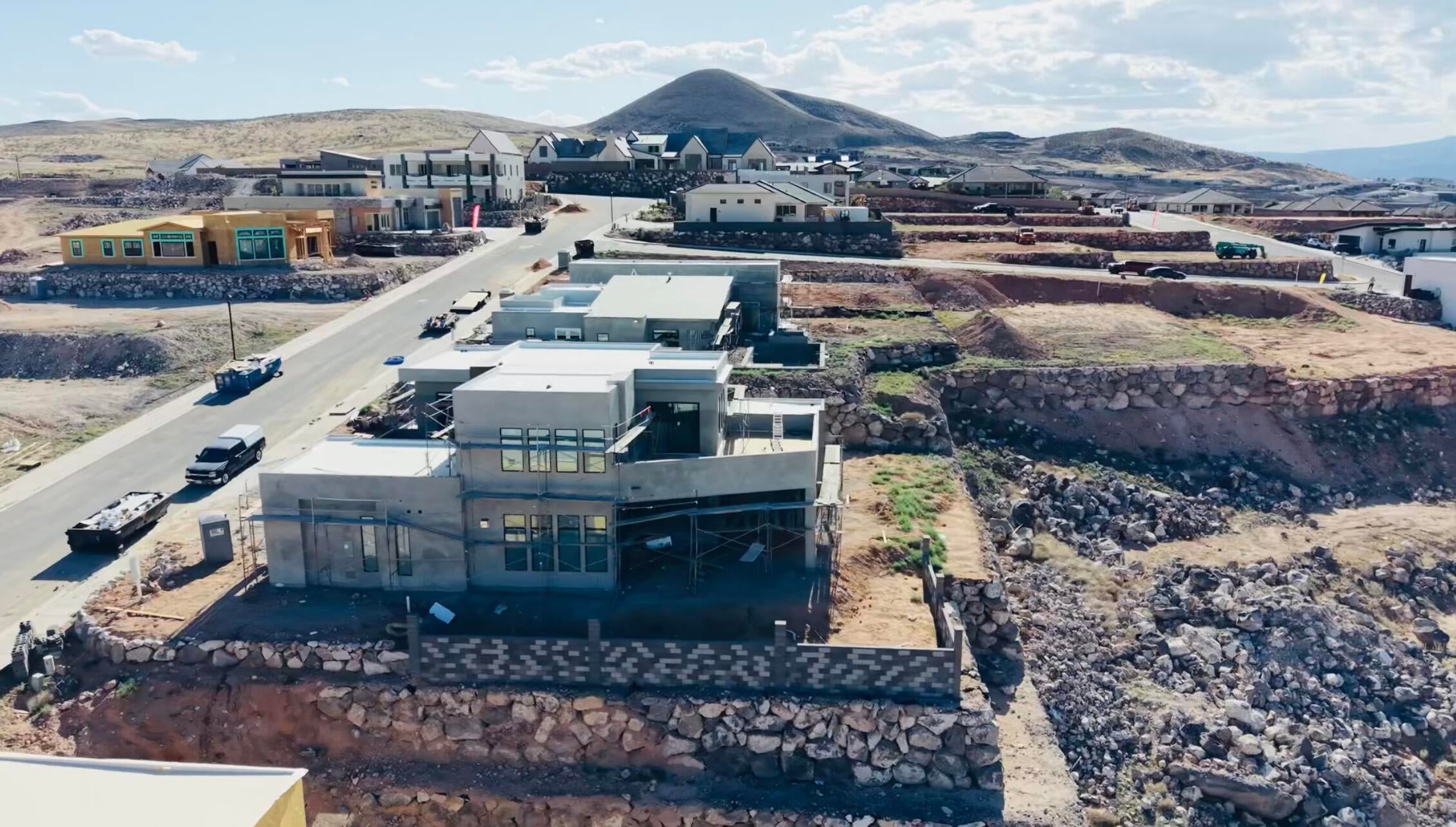 Modern architectural home under construction, featuring multiple levels, expansive window placements, and integrated outdoor terraces