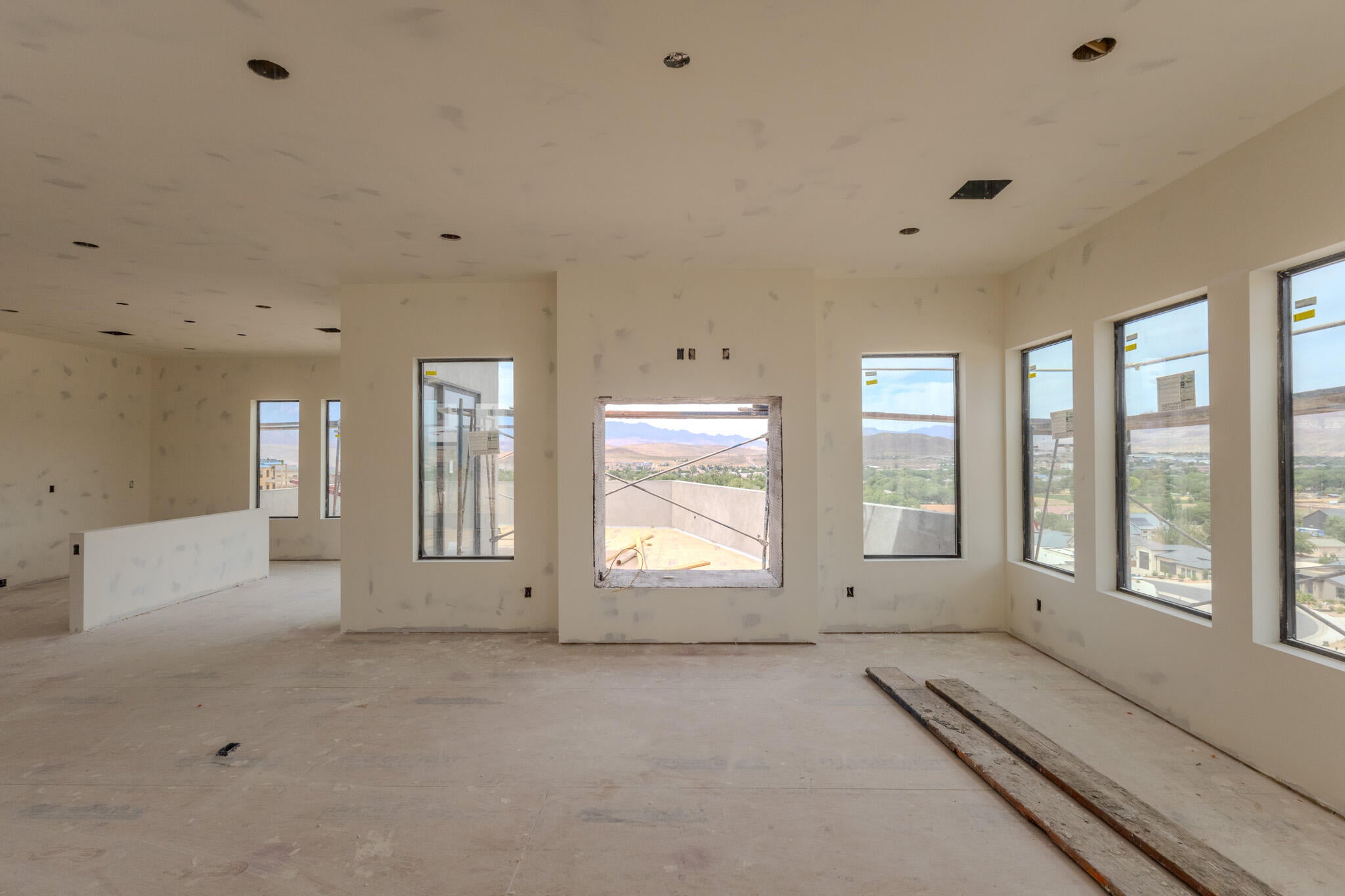 Spacious interior under construction featuring multiple large windows, recessed ceiling lighting, and a central architectural feature